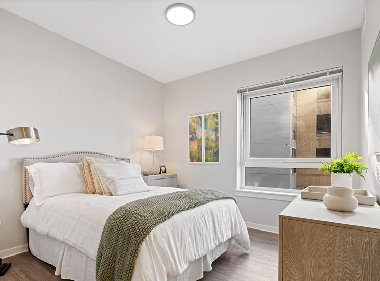 Bedroom with hardwood style flooring and large window at 23rd Place Apartments in Chicago.