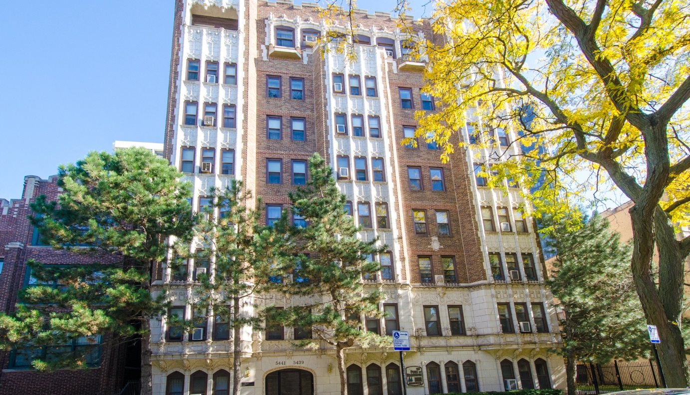 A large building with a yellow tree in front of it.