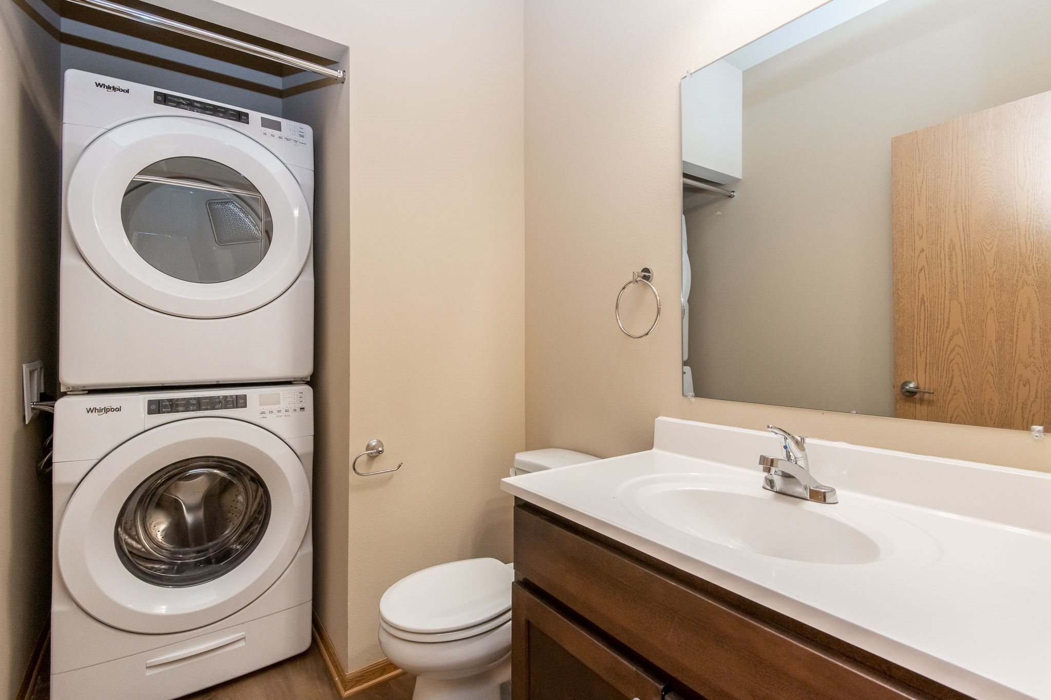 A white washing machine is stacked on top of a white toilet in a small bathroom.