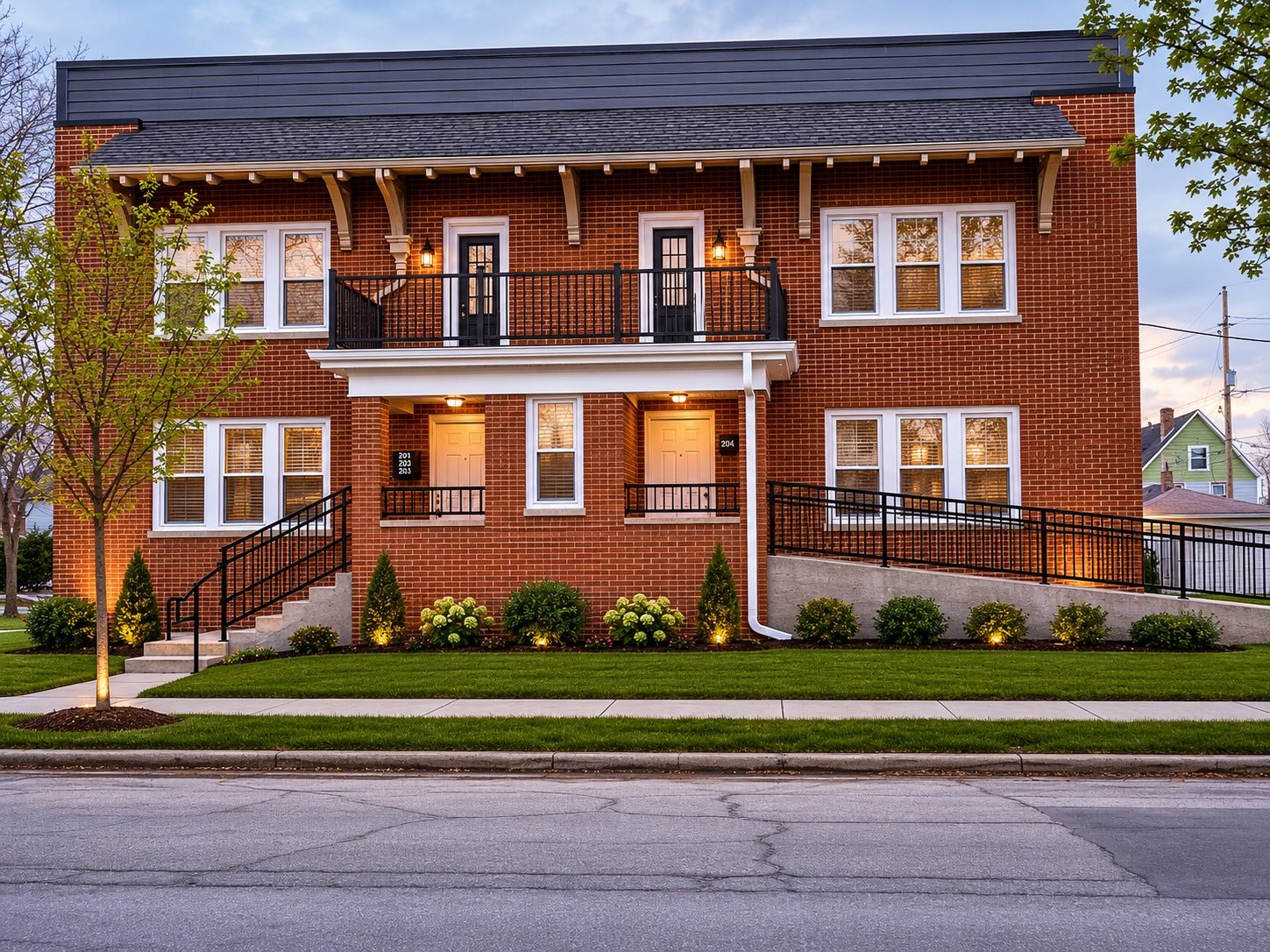 A red brick house with a black metal railing on the balcony.