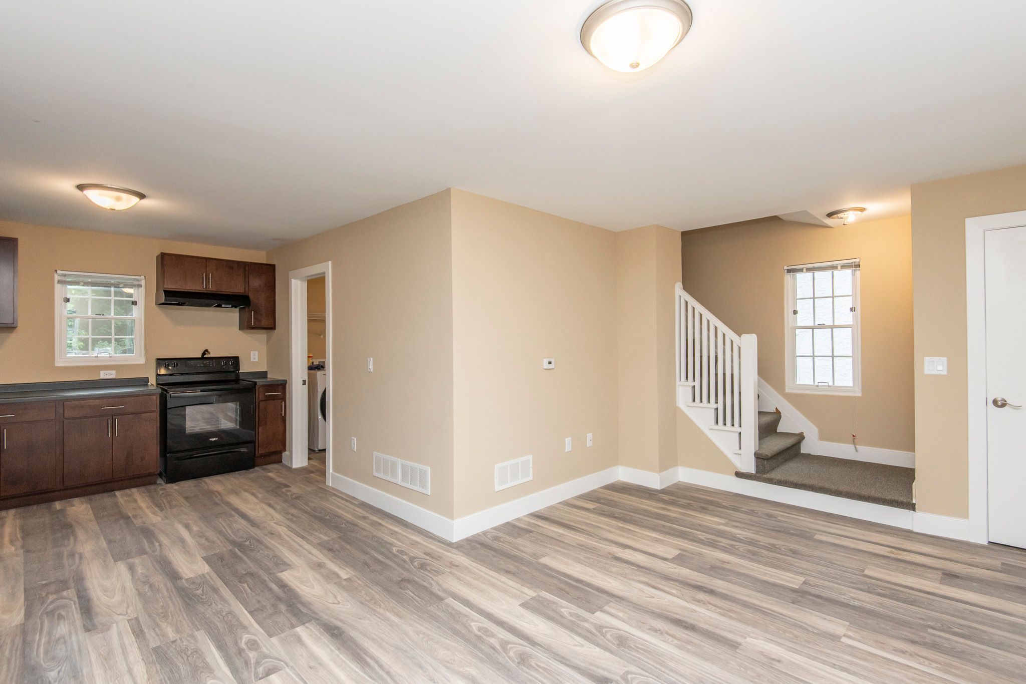 A spacious living room with wood flooring and a staircase leading to another room.