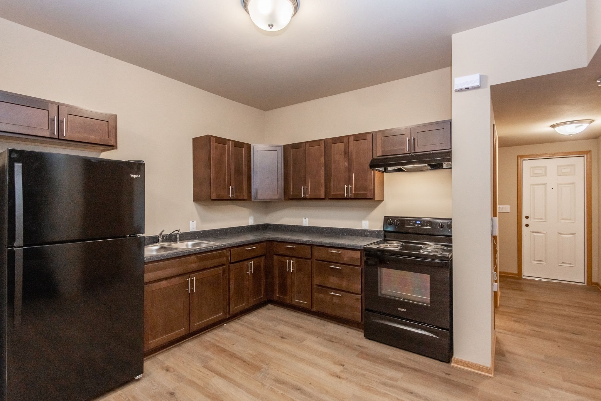 A kitchen with black appliances and wooden cabinets.