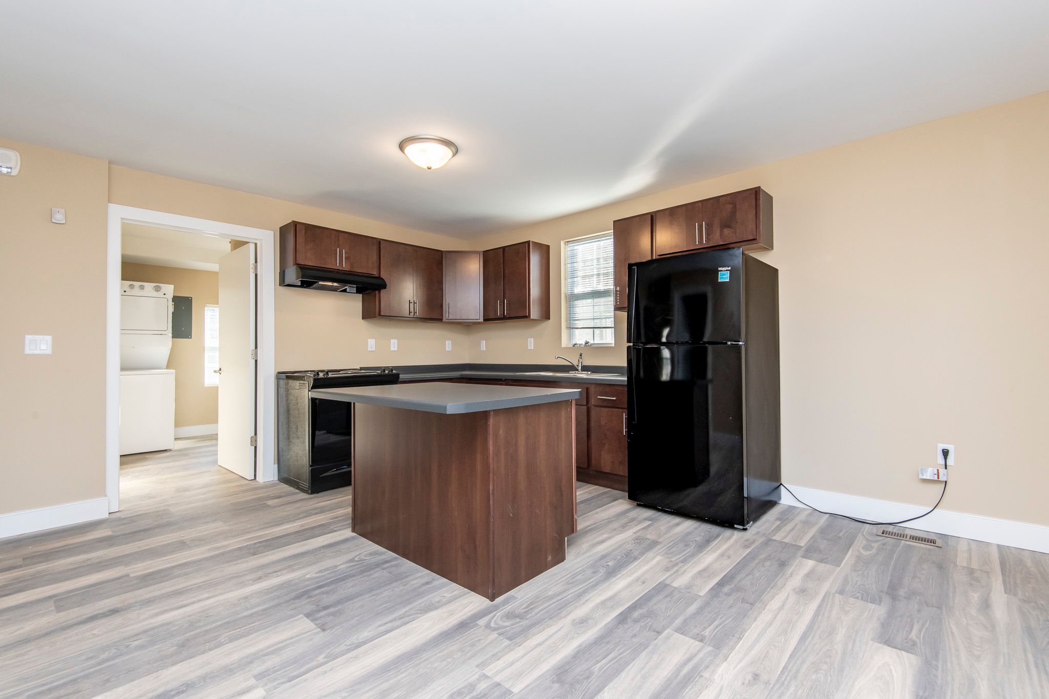 A kitchen with a black fridge and wooden cabinets.