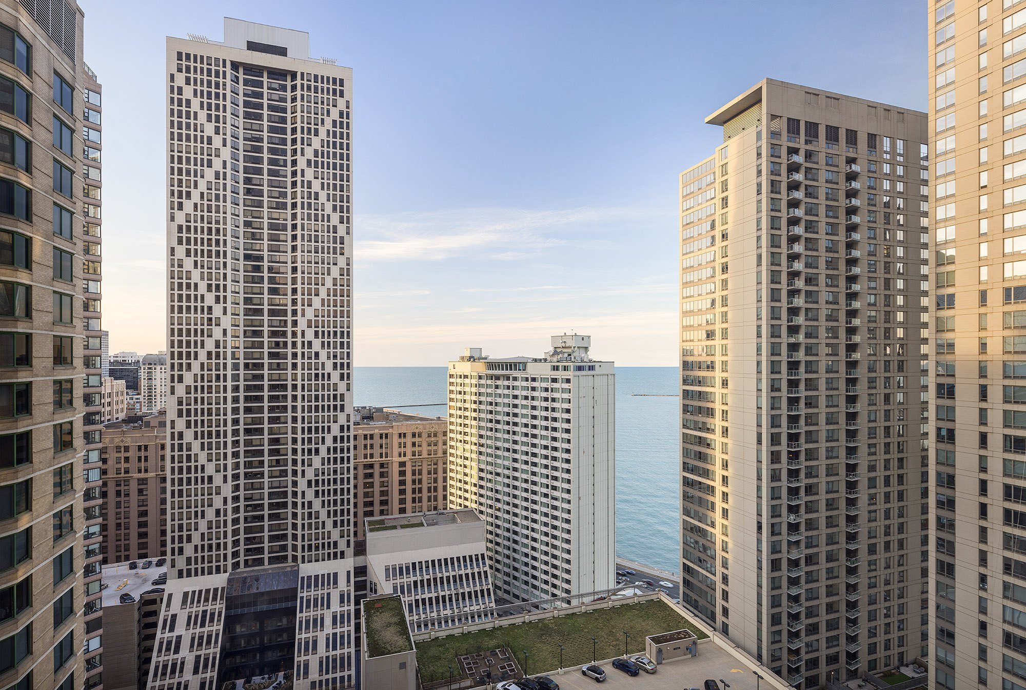 A cityscape with a large building in the middle and a body of water in the background.