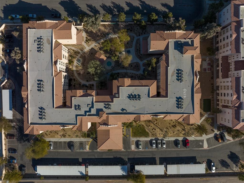 An aerial view of a large building with a parking lot in front.