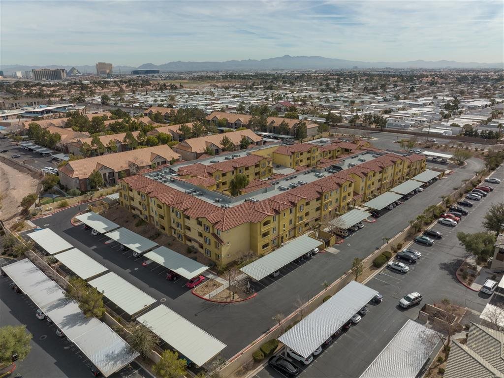 A large apartment complex with a parking lot in front.
