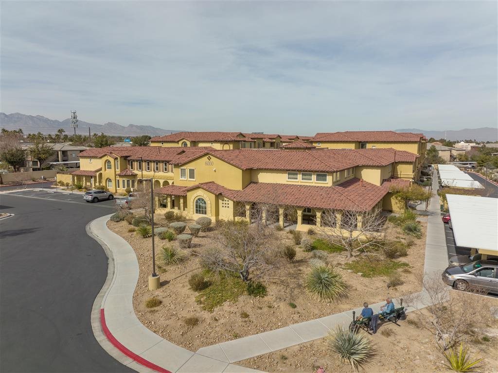 A yellow building with a red roof is surrounded by a desert landscape.