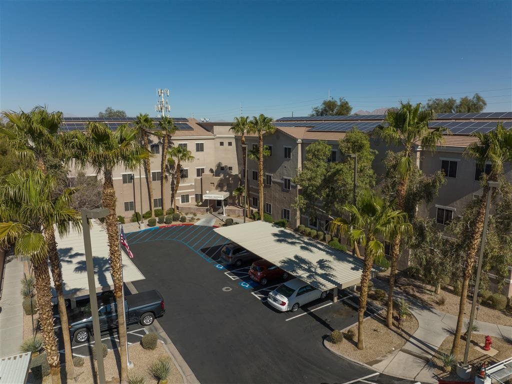 A parking lot with cars and palm trees in front of a building.