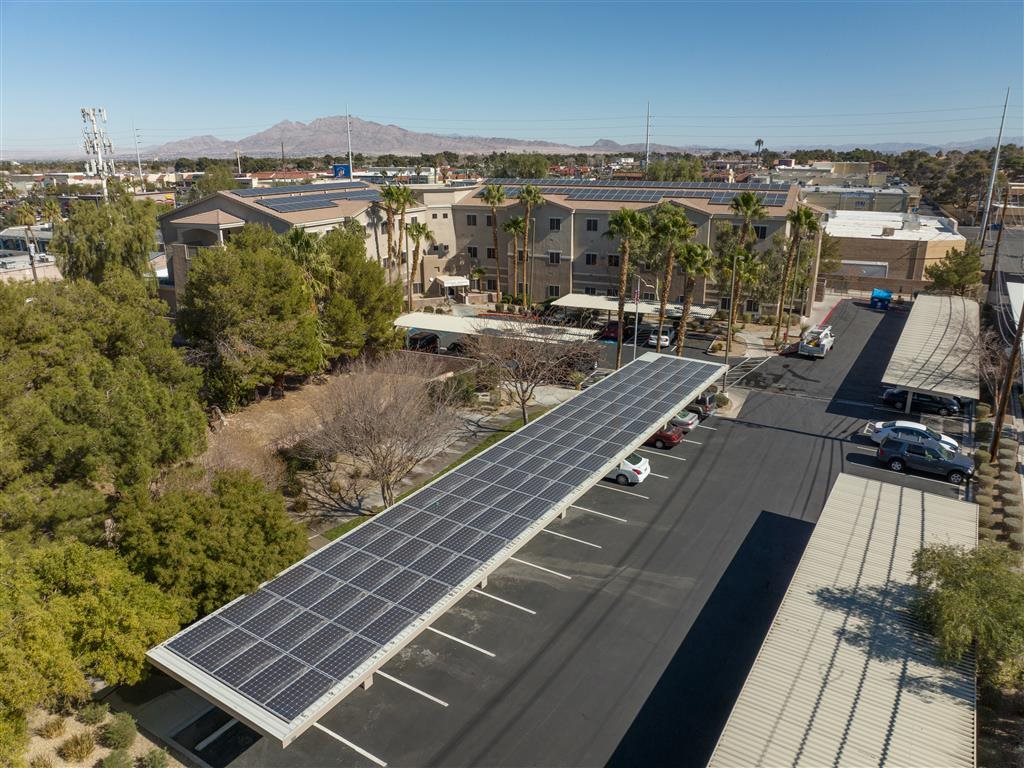 A parking lot with a long row of solar panels on the roof.