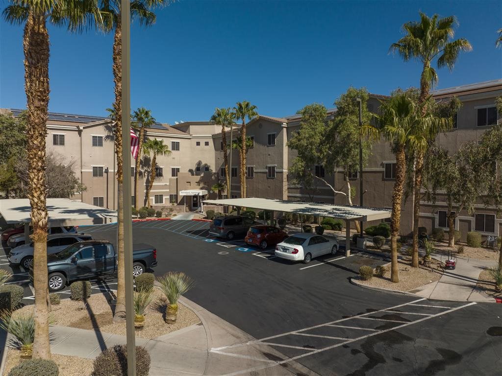 A parking lot with cars and palm trees in front of a building.