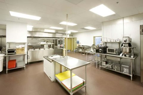 A clean, well-organized commercial kitchen with stainless steel appliances and workstations.