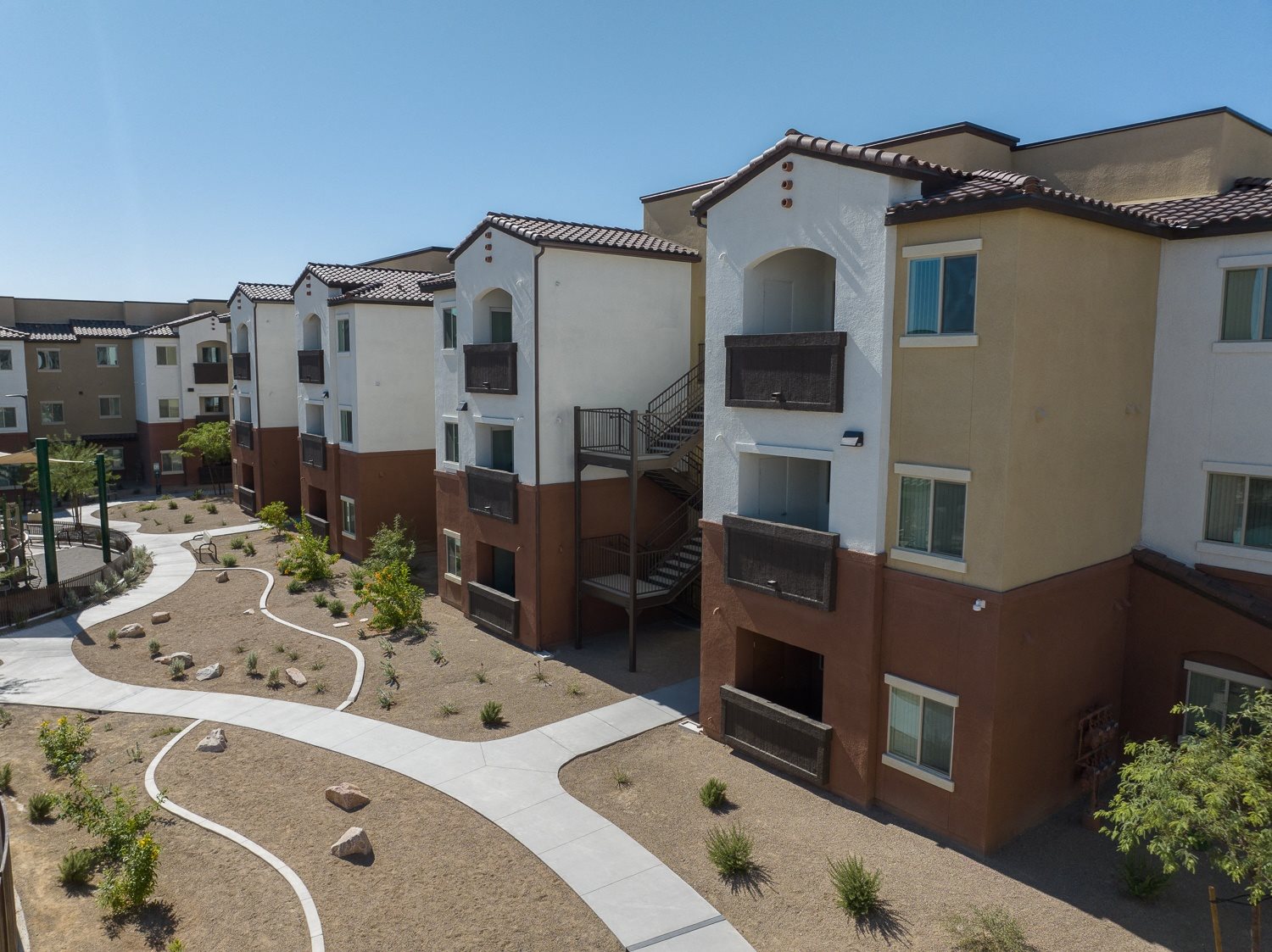 Apartment complex with a pathway and landscaping.