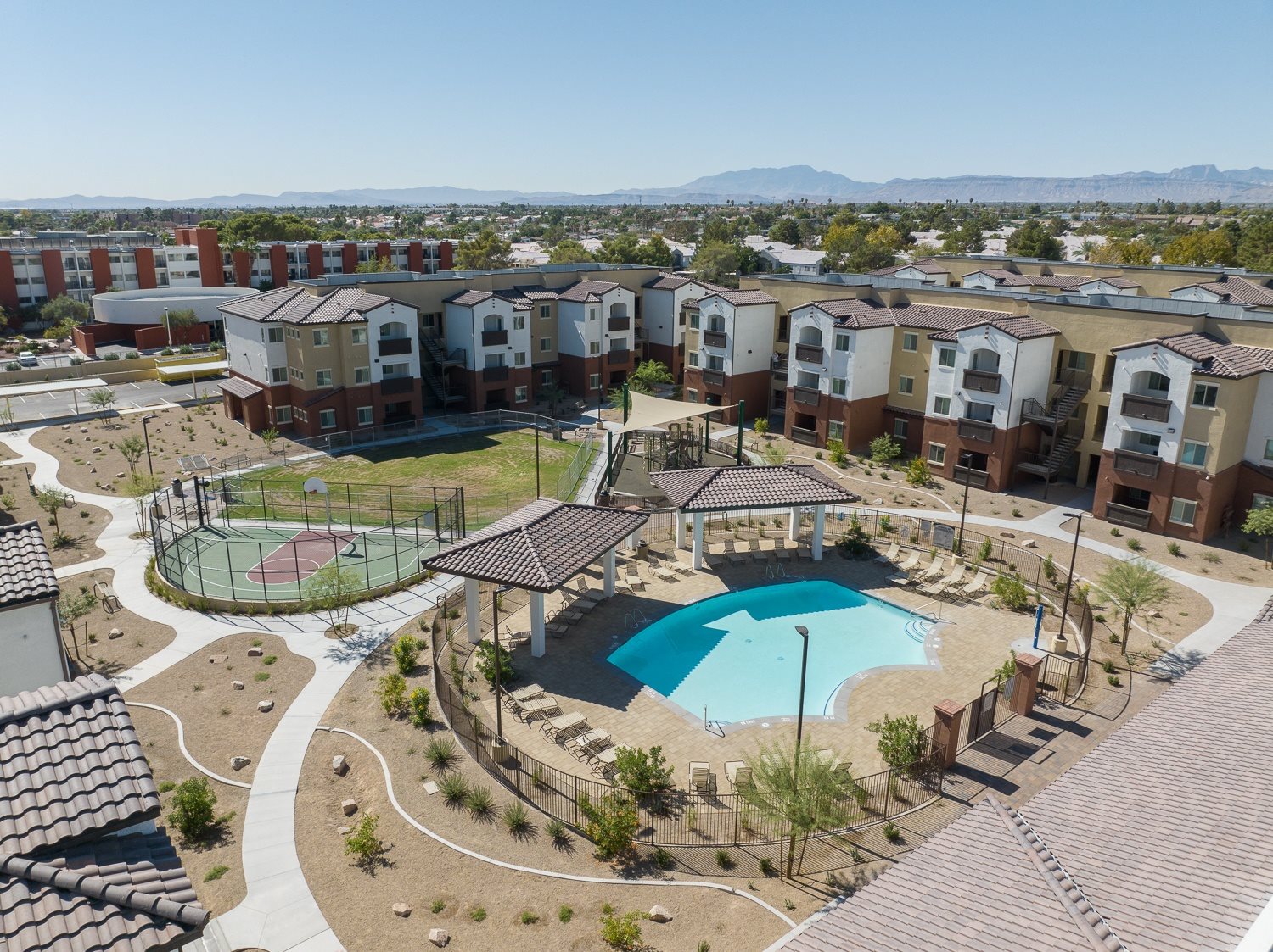 A large swimming pool surrounded by a fence and a gazebo in the middle of a courtyard.