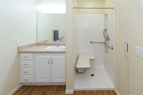 A small bathroom with a sink, mirror, and shower.
