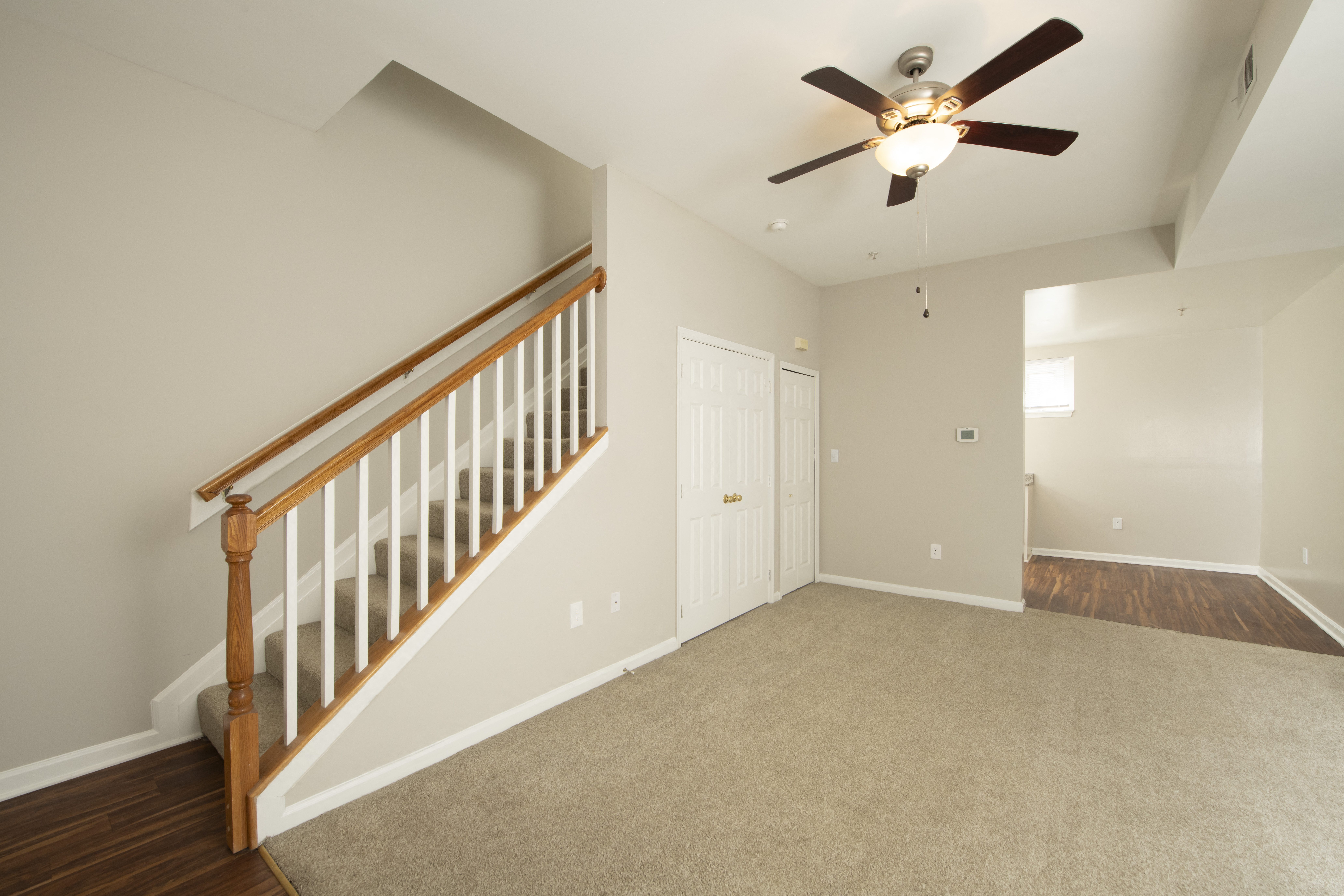 an empty living room with a ceiling fan and a staircase at Queen Anne Belvedere, Baltimore, Maryland