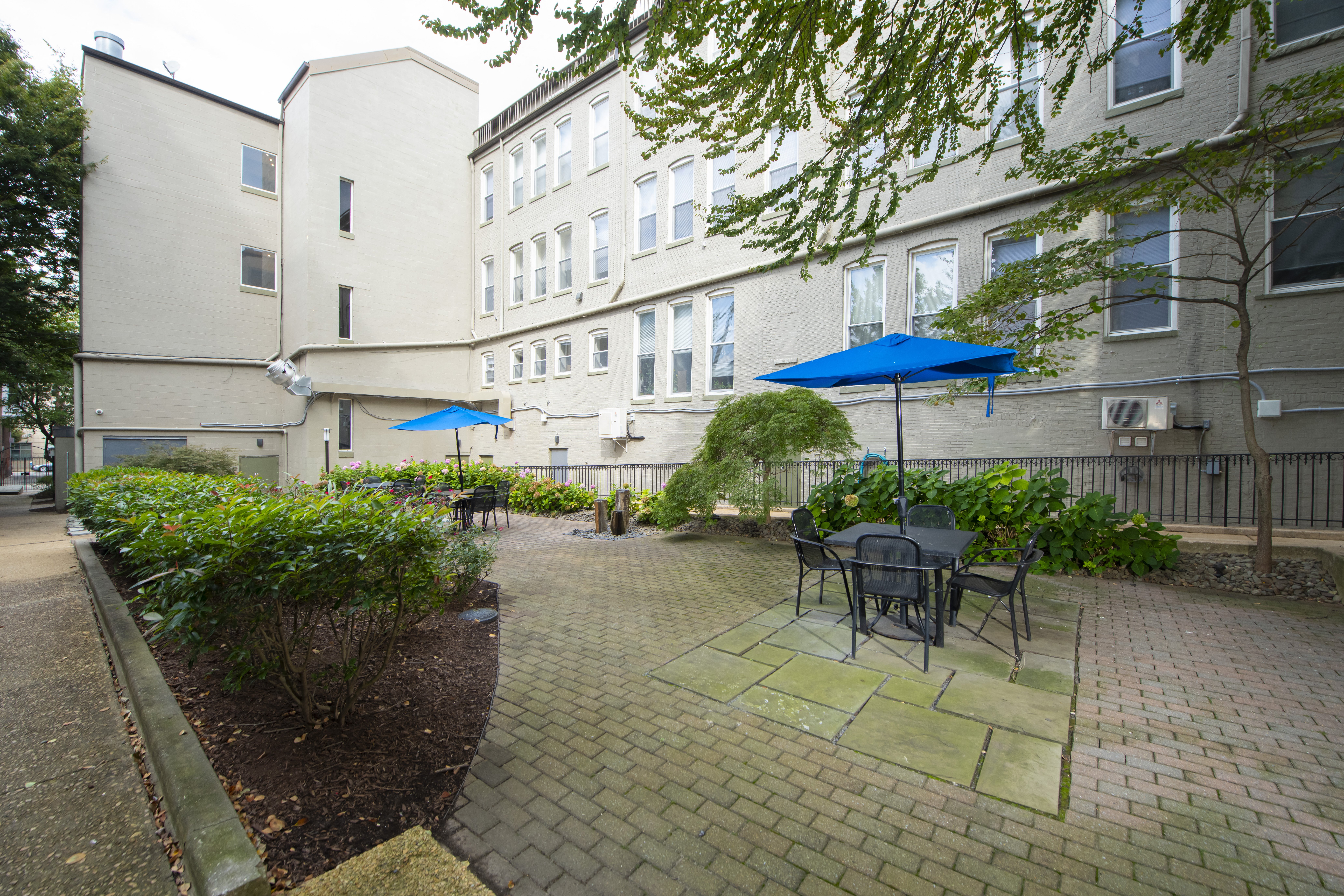 a patio with tables and umbrellas in a courtyard at Queen Anne Belvedere, Baltimore, MD