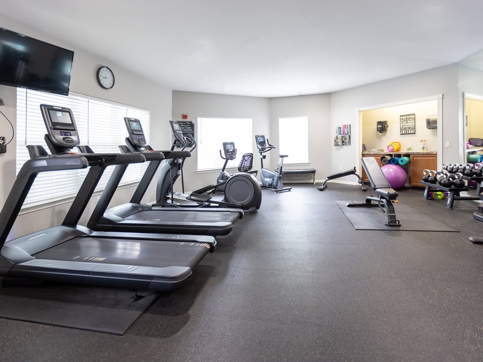 A spacious gym with treadmills, exercise equipment, and a television.