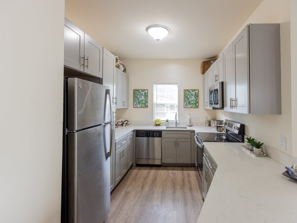A kitchen with a refrigerator, sink, and cabinets.