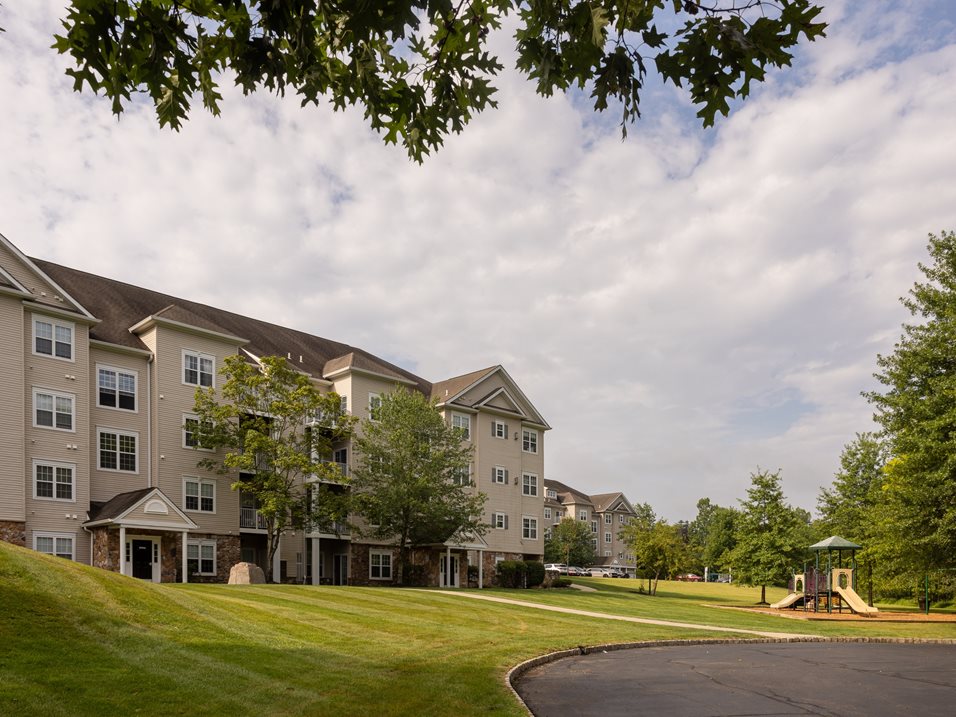 A large apartment complex with a playground in the front.