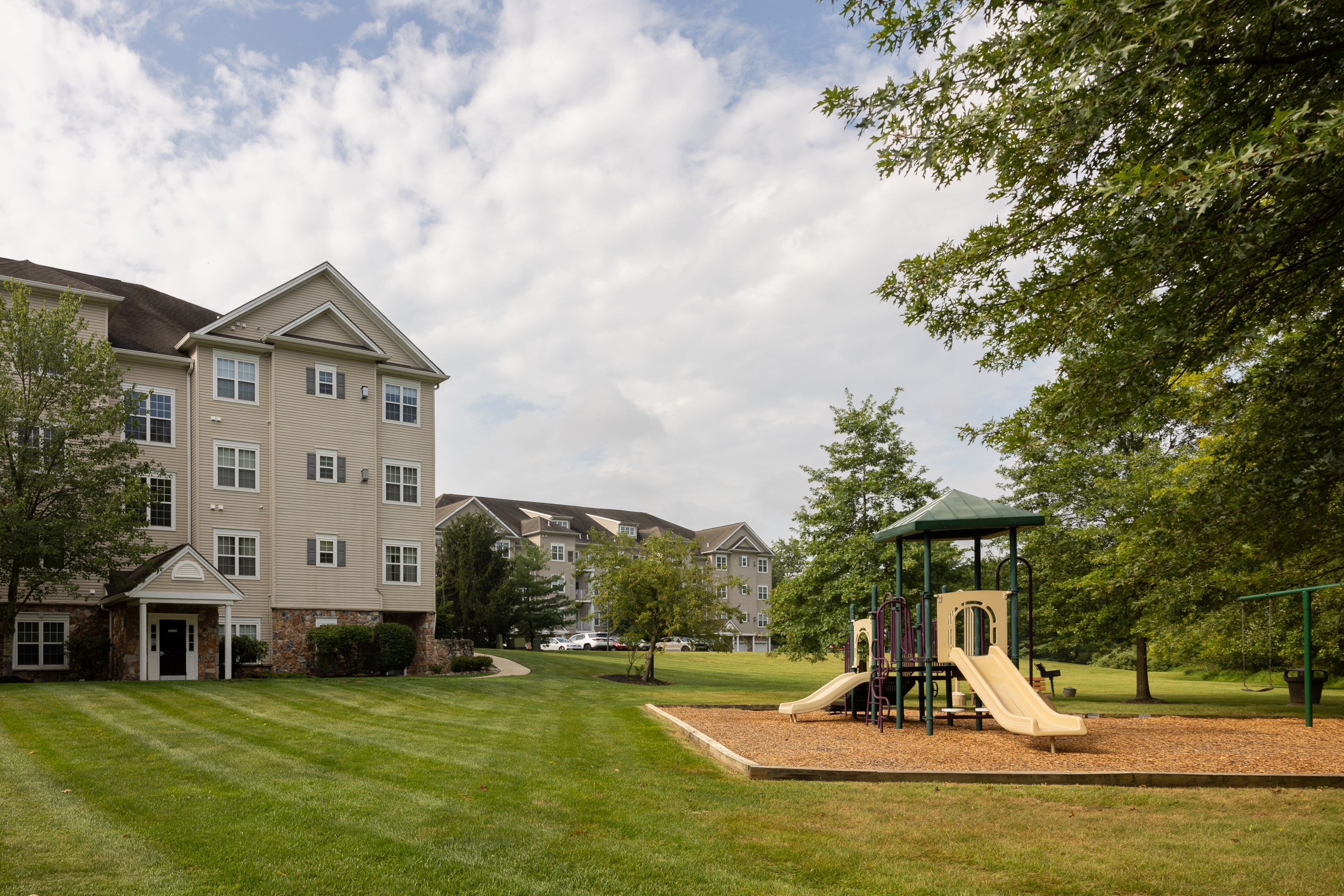 A playground with a slide and a building in the background.