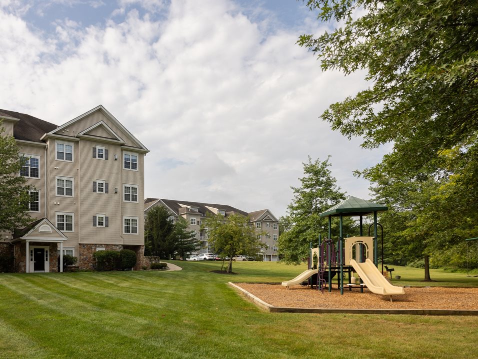 A playground with a slide and a building in the background.