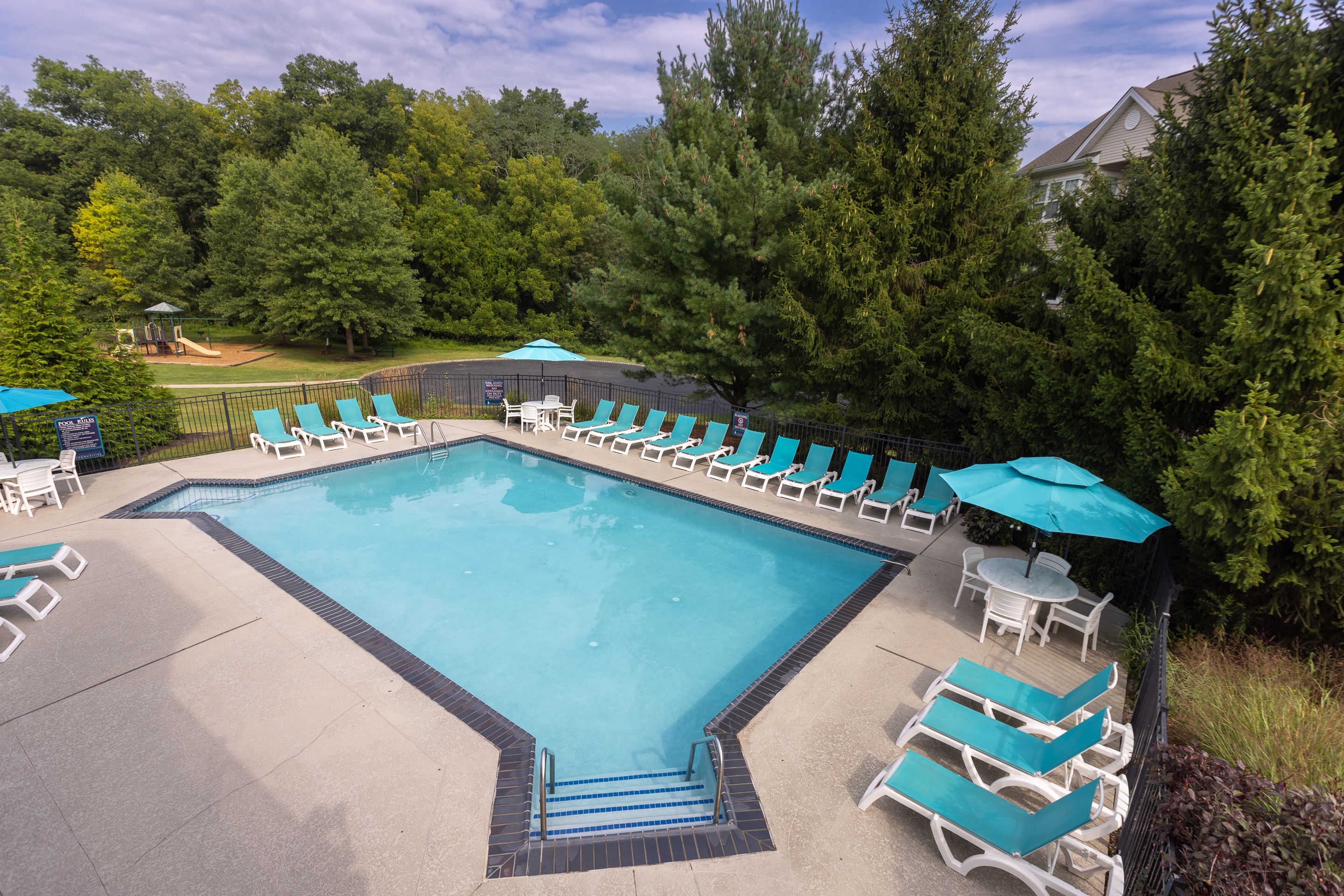 A large swimming pool surrounded by trees and lounge chairs.