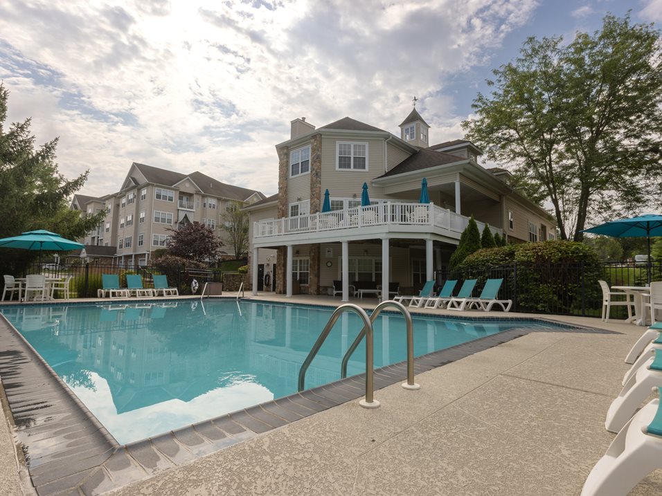 A large swimming pool in front of a resort style building.