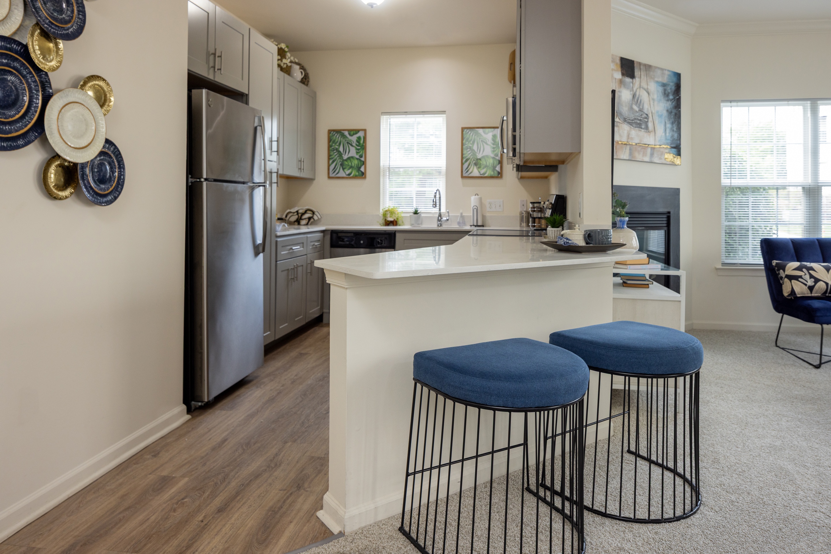 A kitchen with a white counter and blue stools.