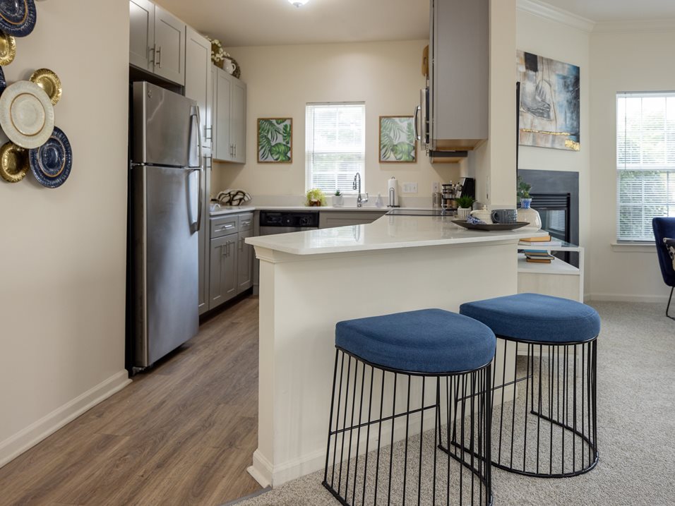 A kitchen with a white counter and blue stools.