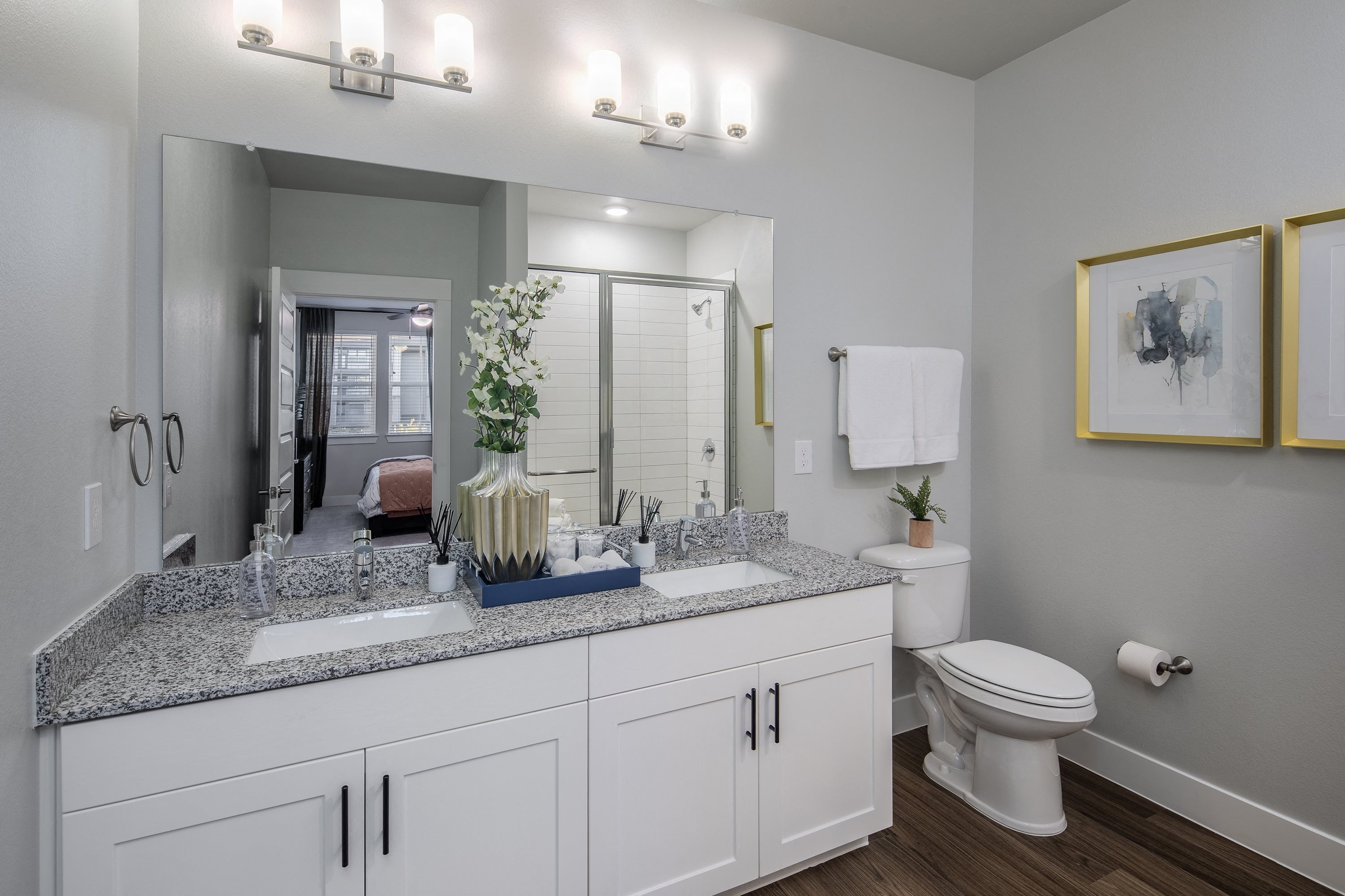 a bathroom with a double sink and a toilet and a mirror at a senior apartment community