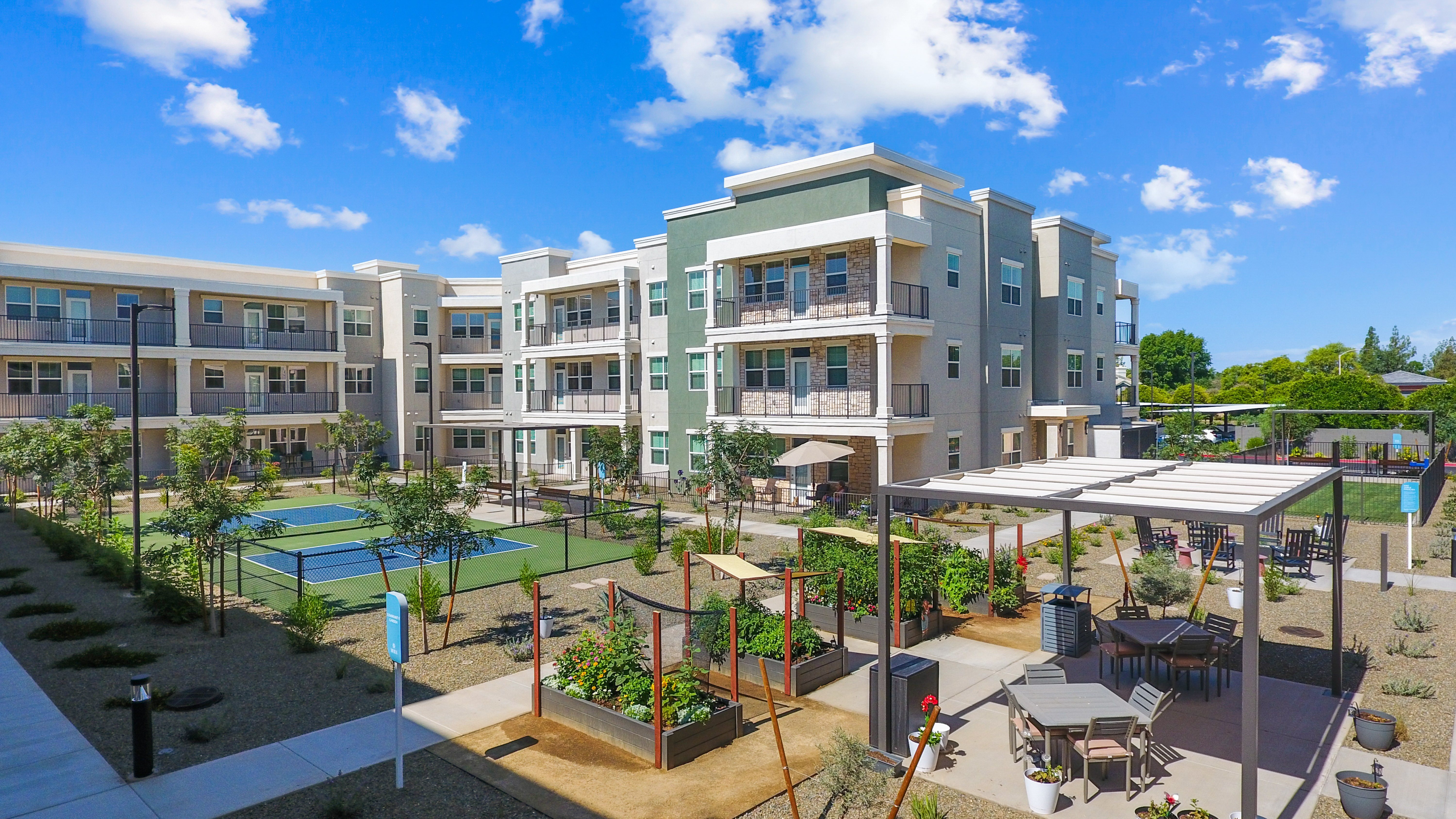 A modern apartment complex with a pool and outdoor seating area.
