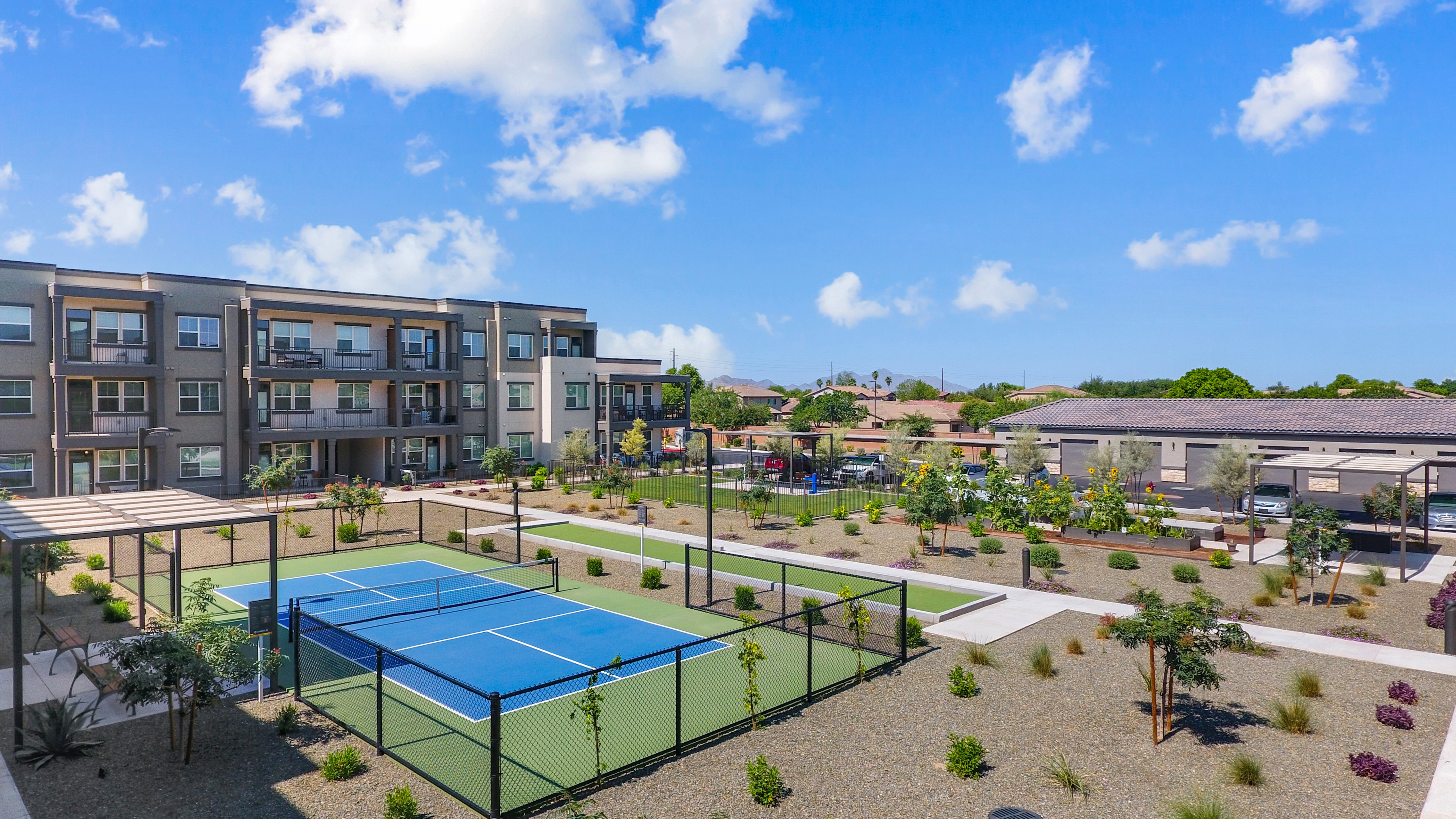 A tennis court is surrounded by apartment buildings.