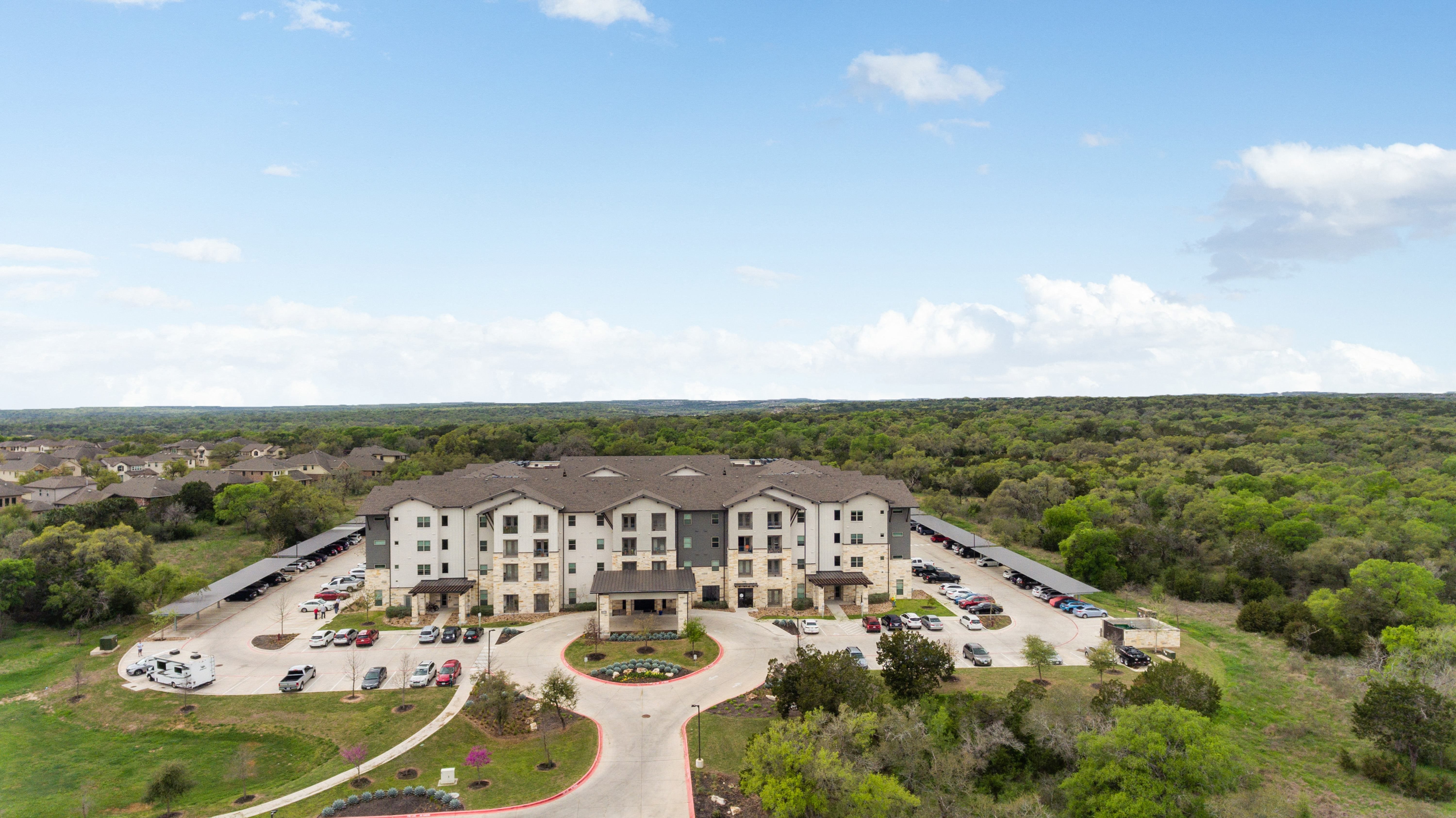 an aerial view of a senior apartment community and the surrounding land with trees