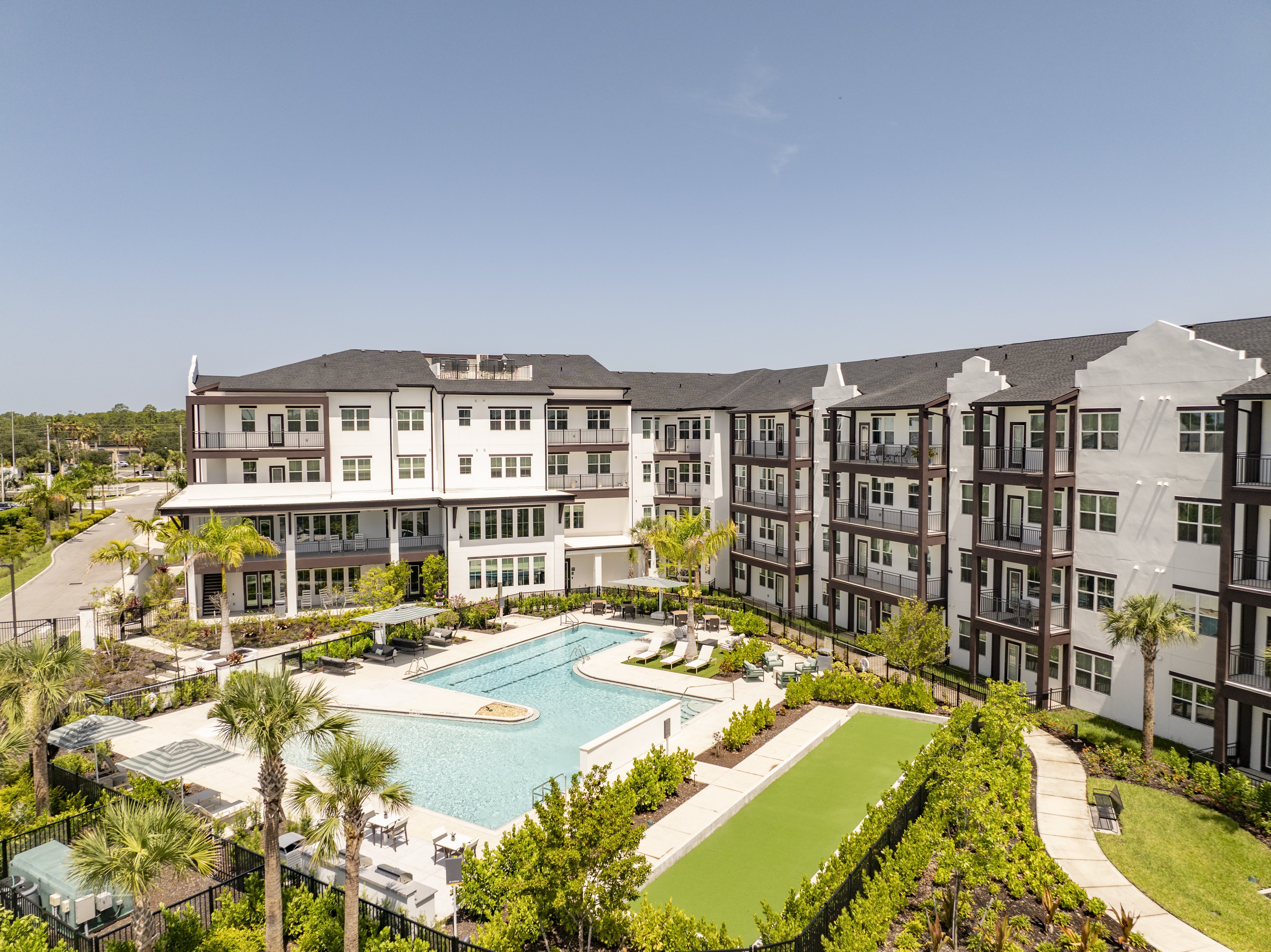 A large apartment complex with a pool and palm trees.