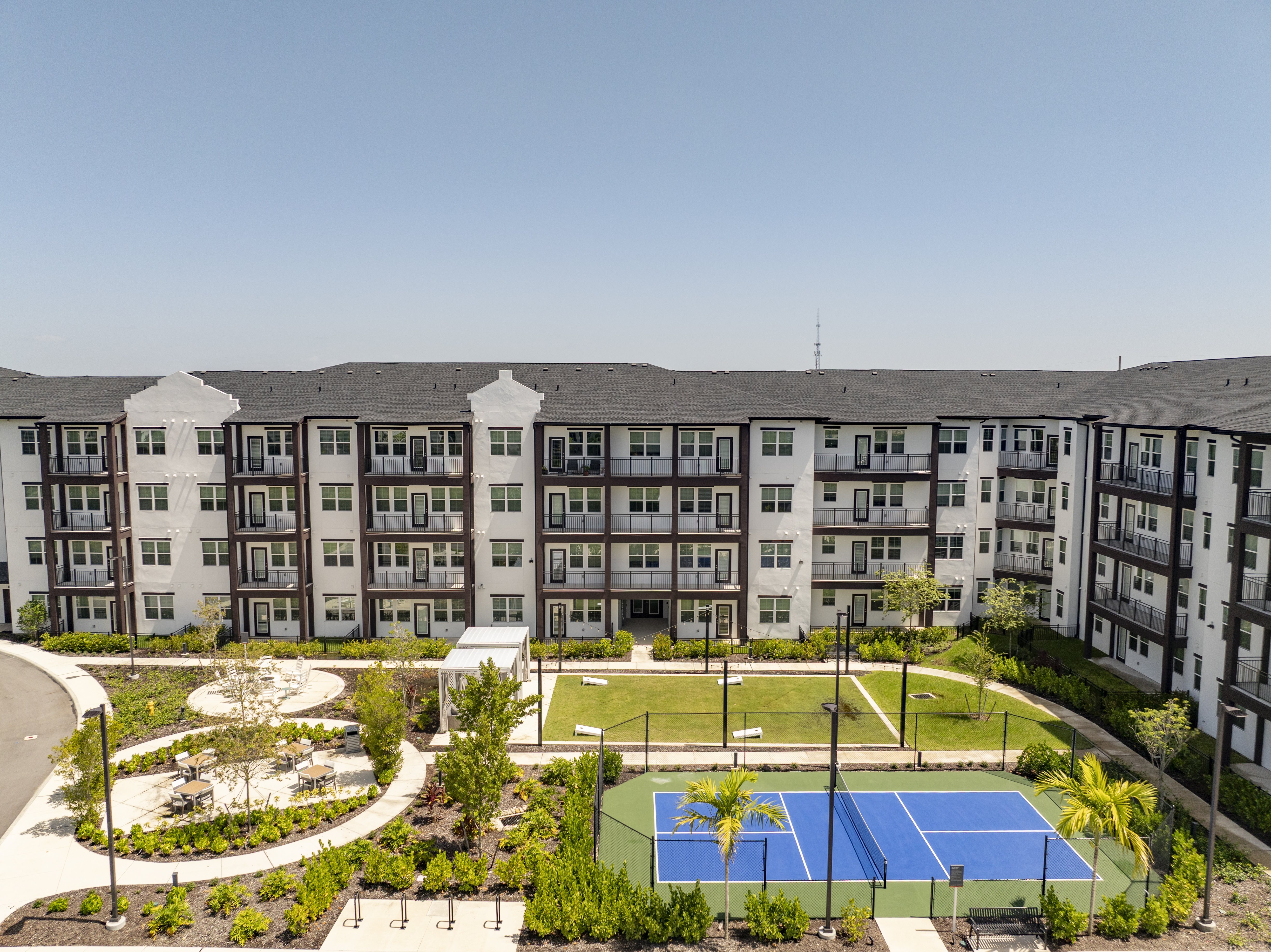 A tennis court is located in the middle of a courtyard surrounded by apartment buildings.