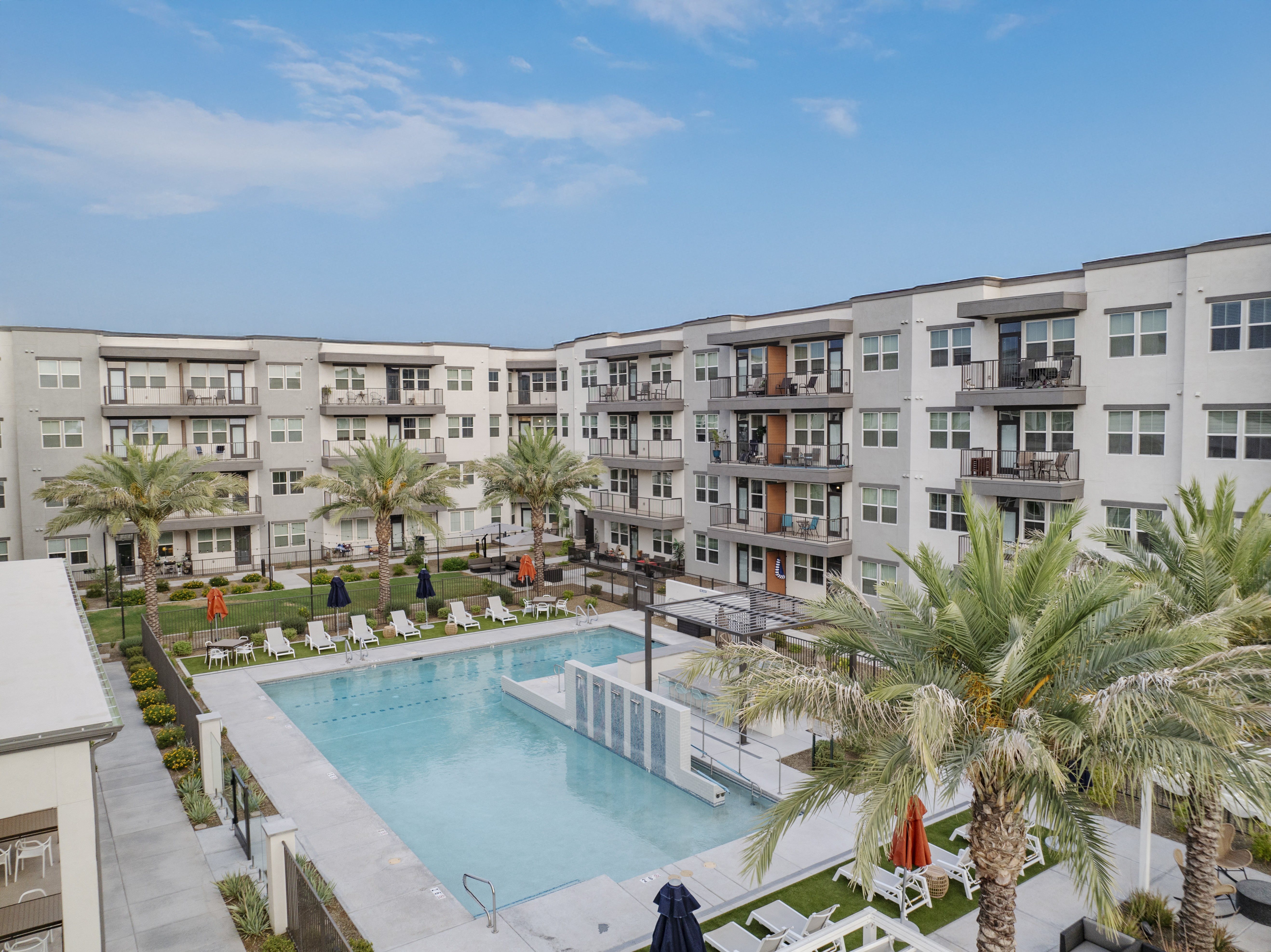 a large pool with palm trees in front of an apartment building