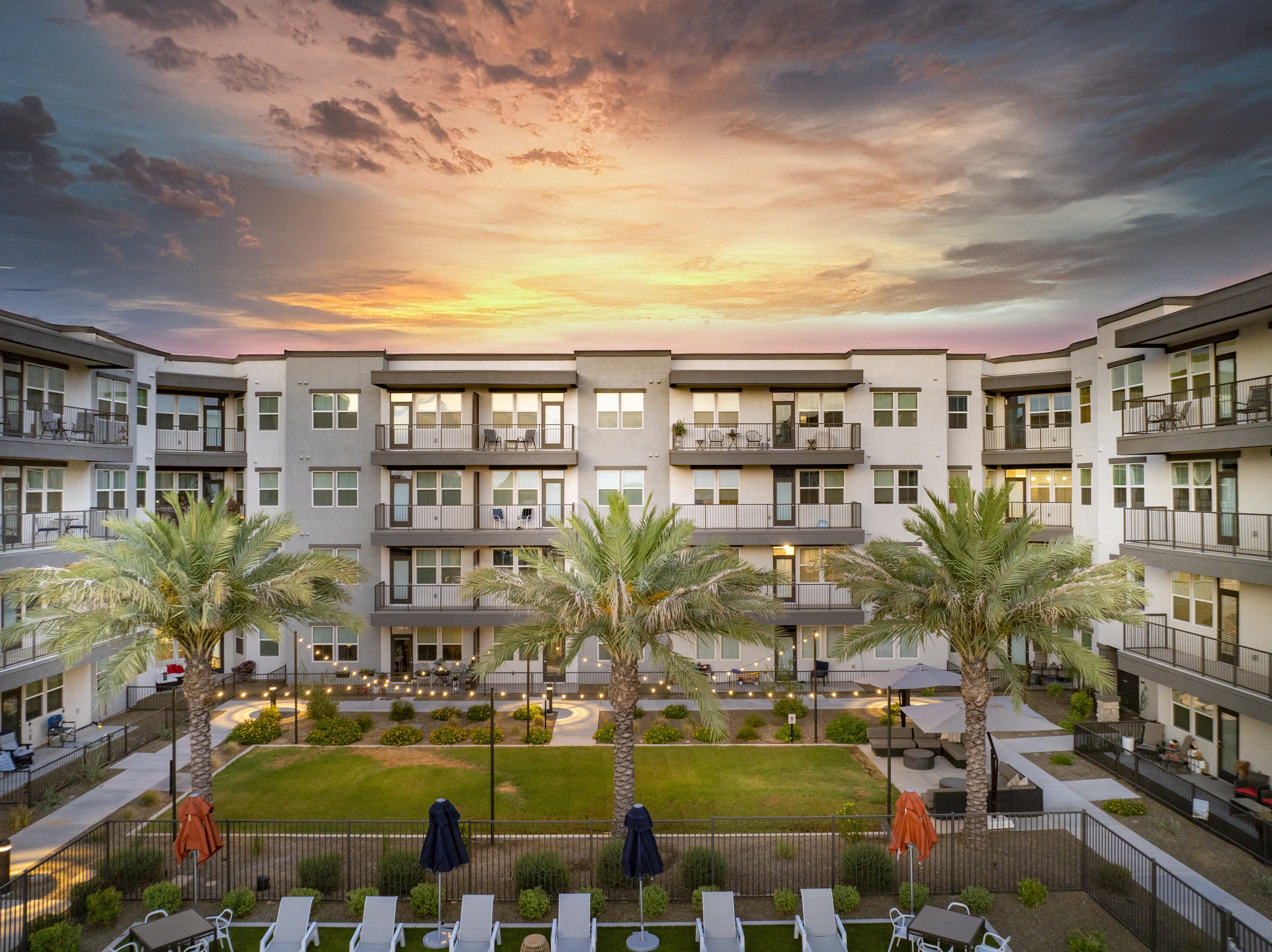A sunset view of a residential area with apartment buildings and palm trees.