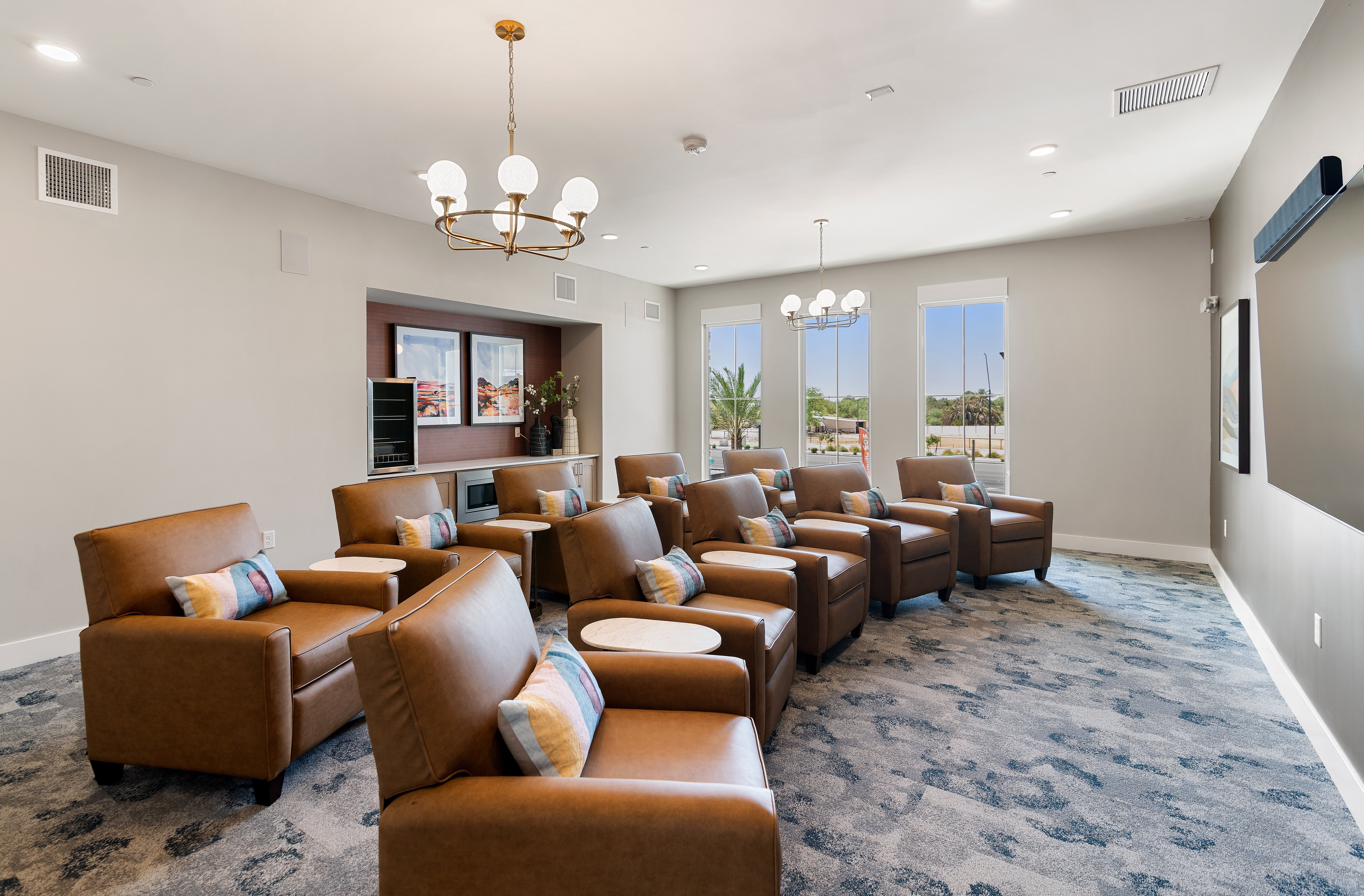 A living room with brown leather chairs and a chandelier.