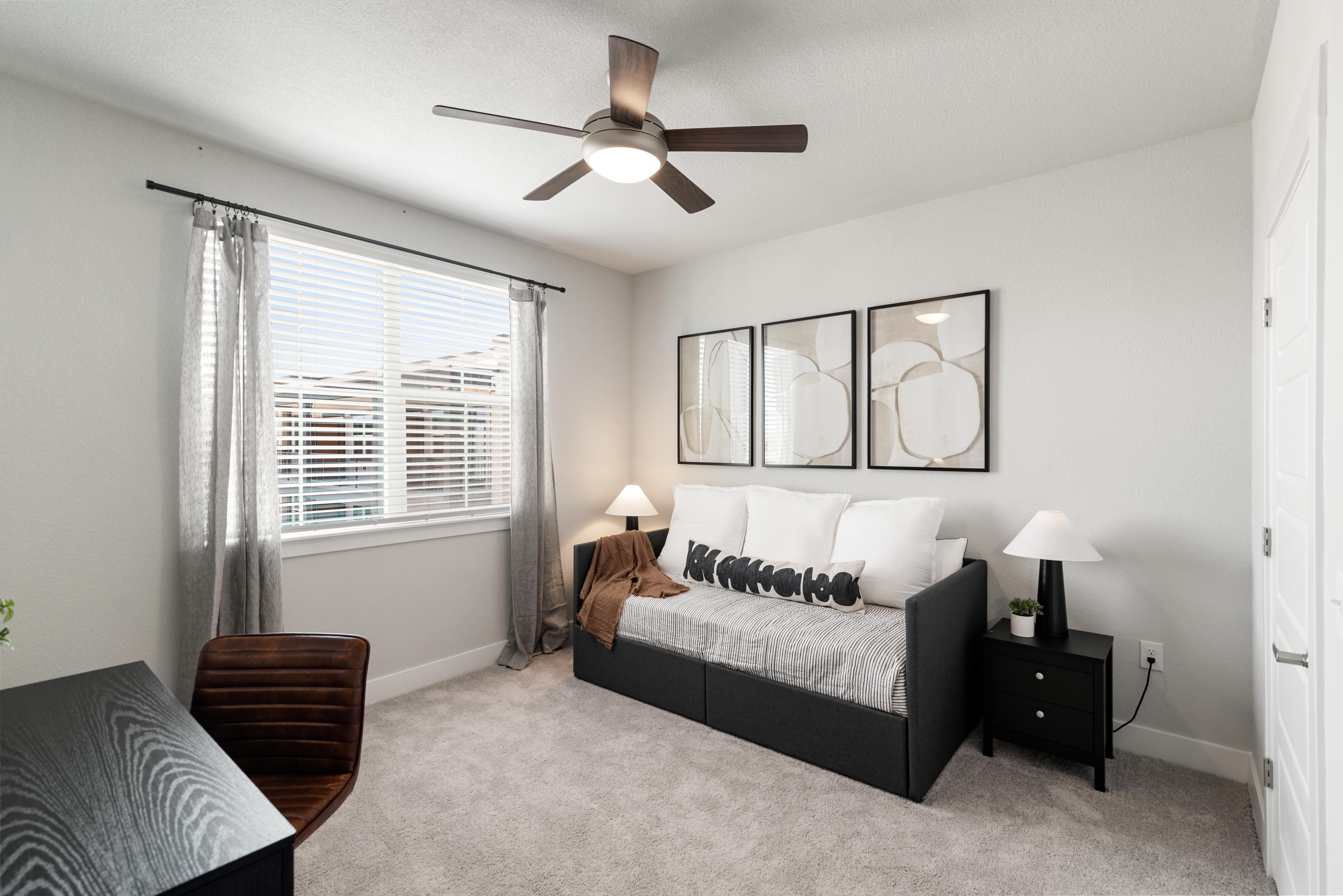 A bedroom with a bed, nightstand, and a ceiling fan.