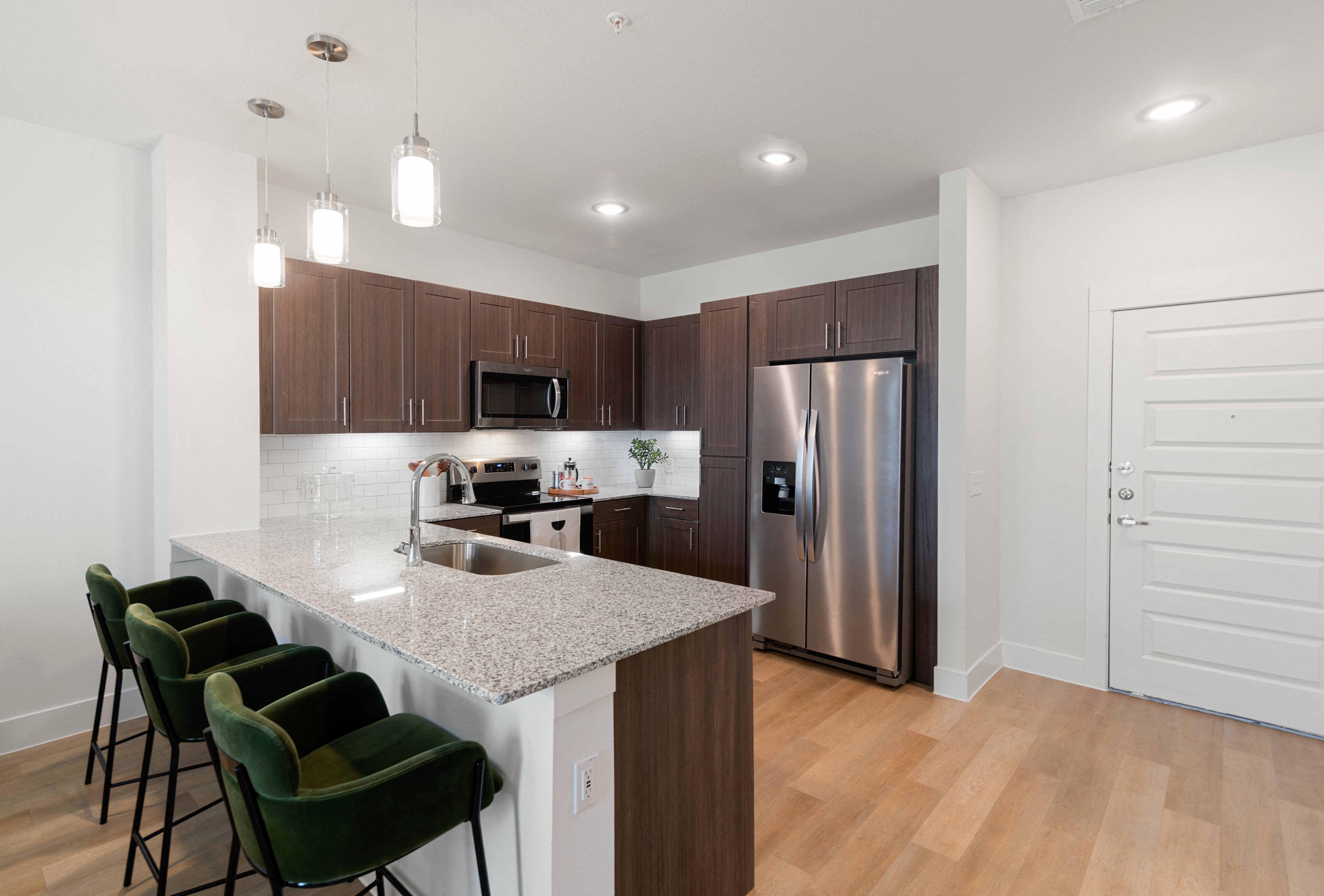 a kitchen with a marble counter top and a stainless steel refrigerator