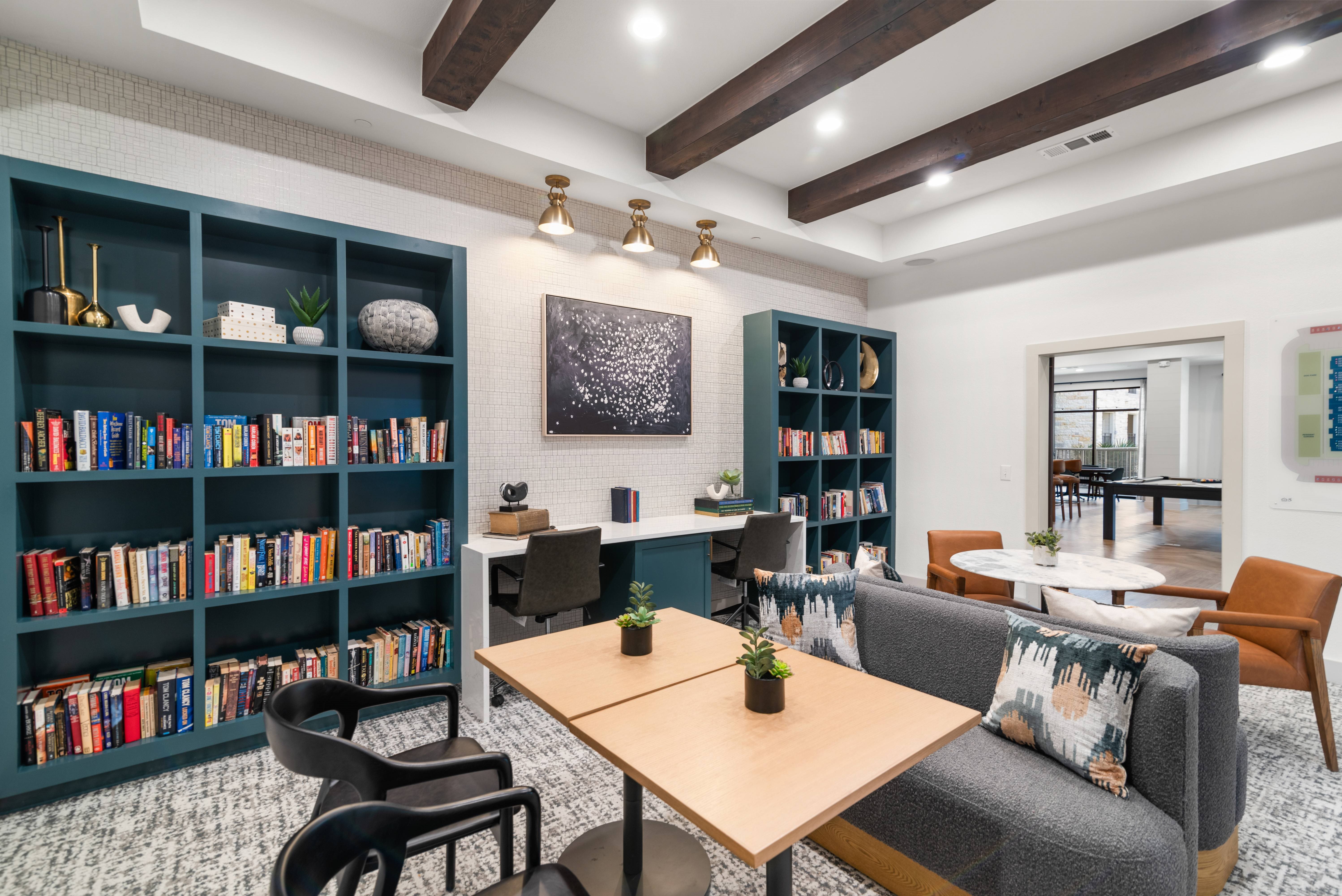A living room with a bookshelf filled with books and a grey couch.
