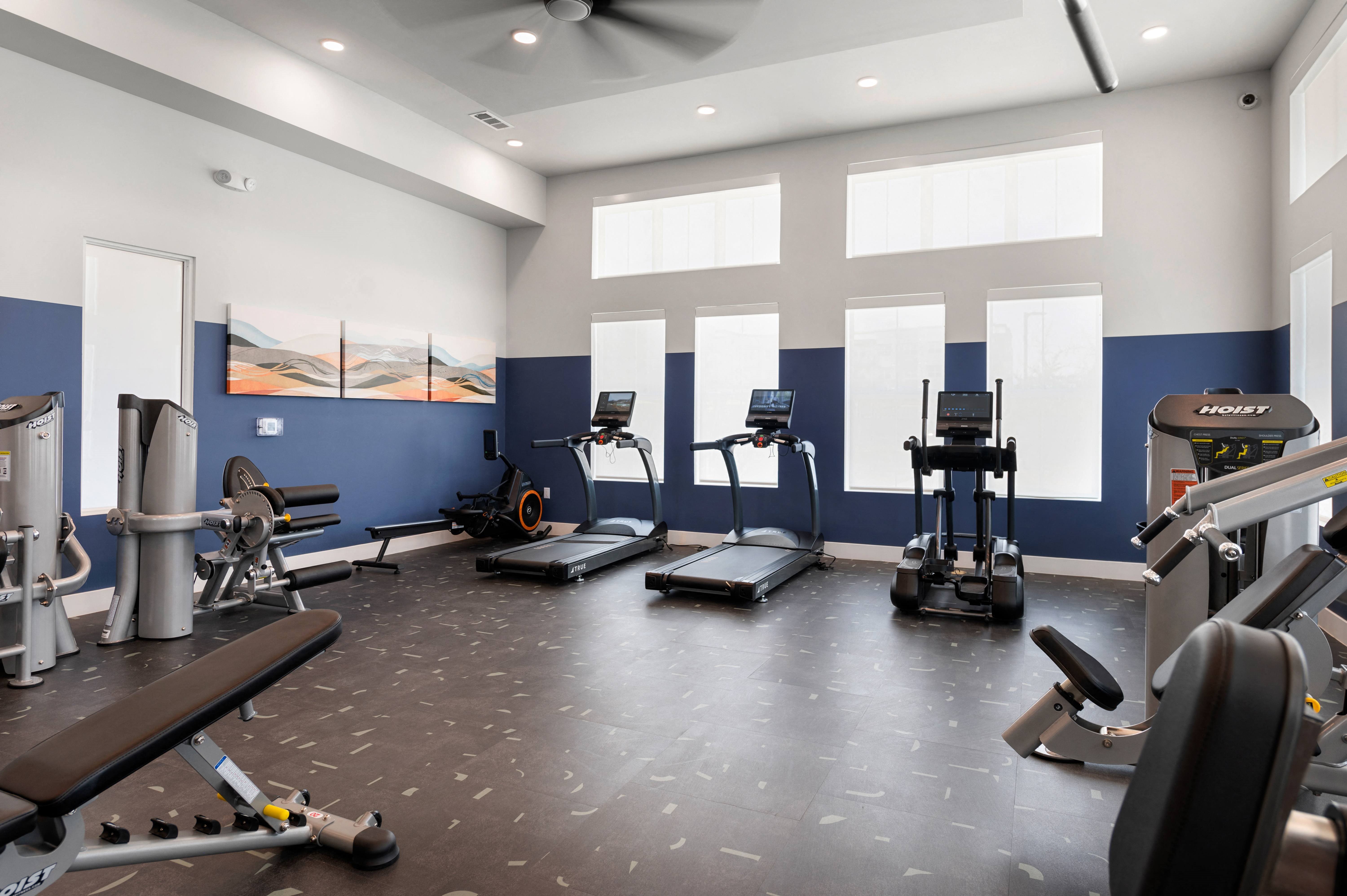 a gym with various exercise equipment on the floor and windows