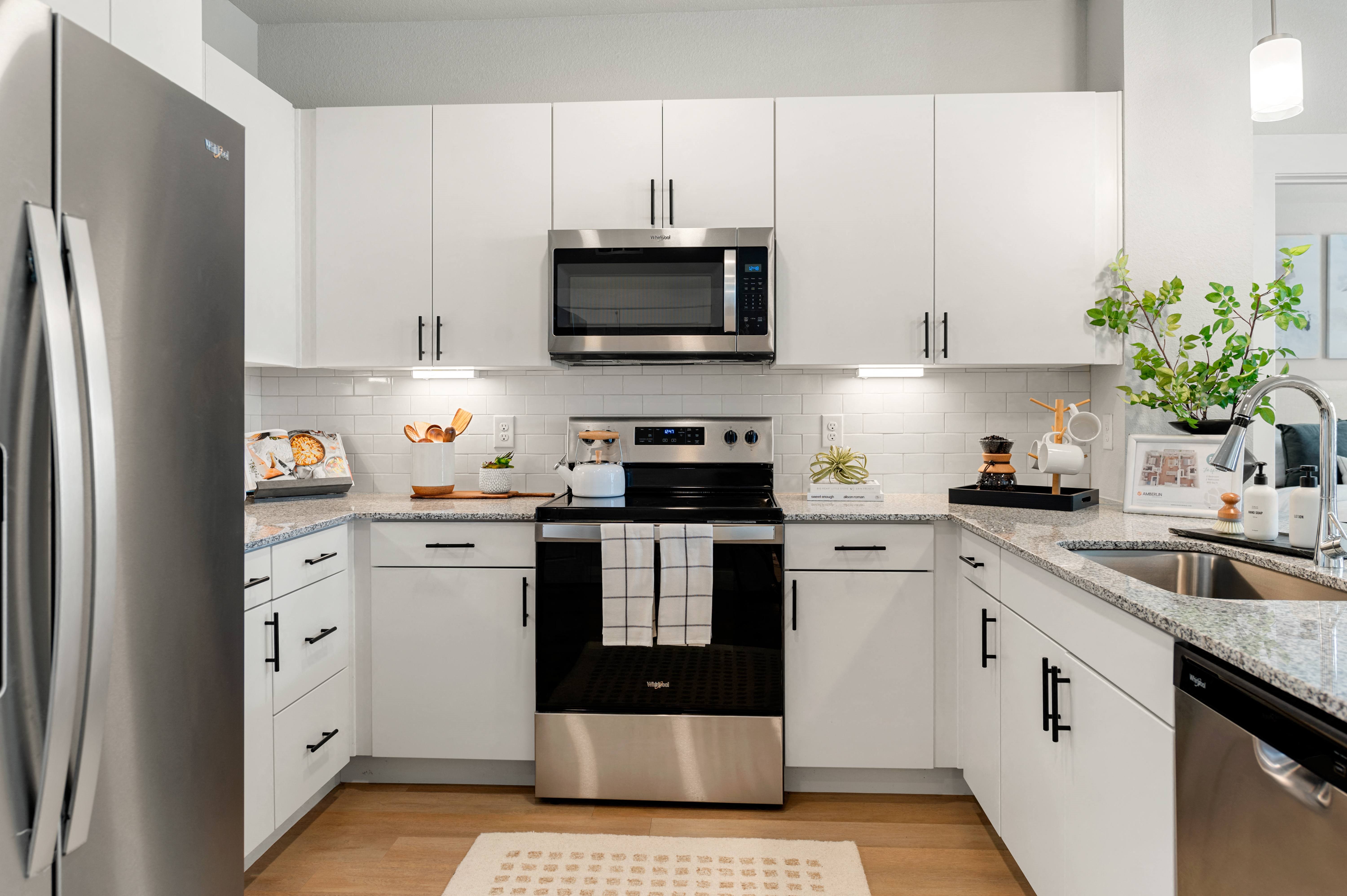 a white kitchen with stainless steel appliances and white cabinets