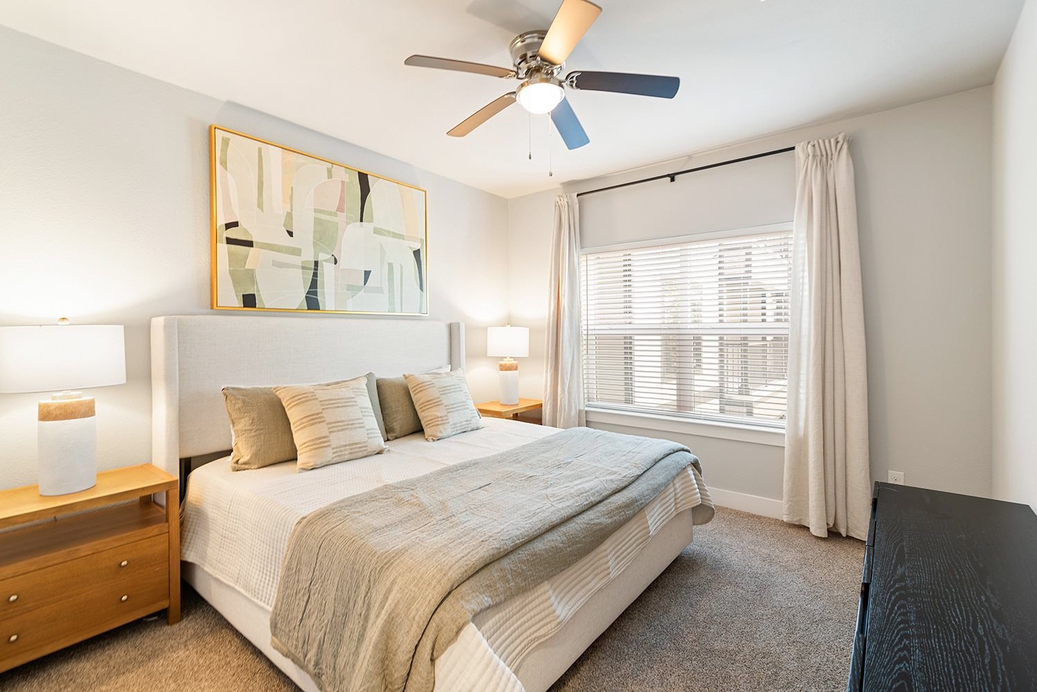 A bedroom with a bed, nightstand, and a painting on the wall.