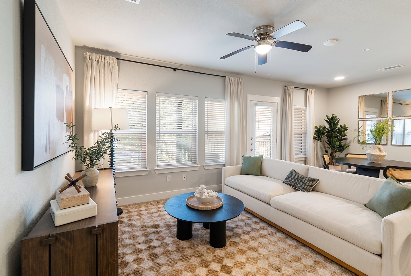 A living room with a white couch, a coffee table, and a ceiling fan.