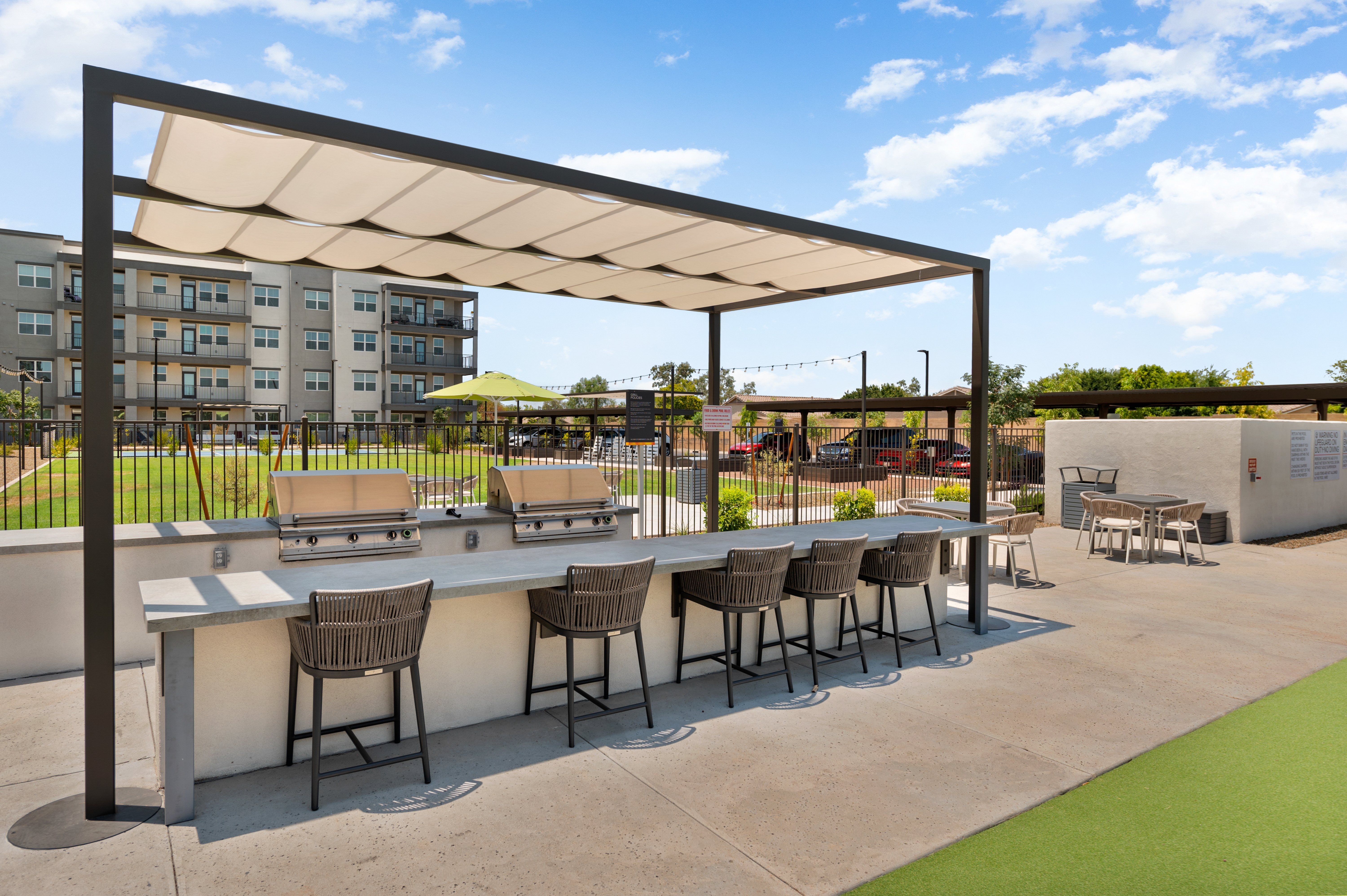 A patio with a bar and chairs under a canopy.
