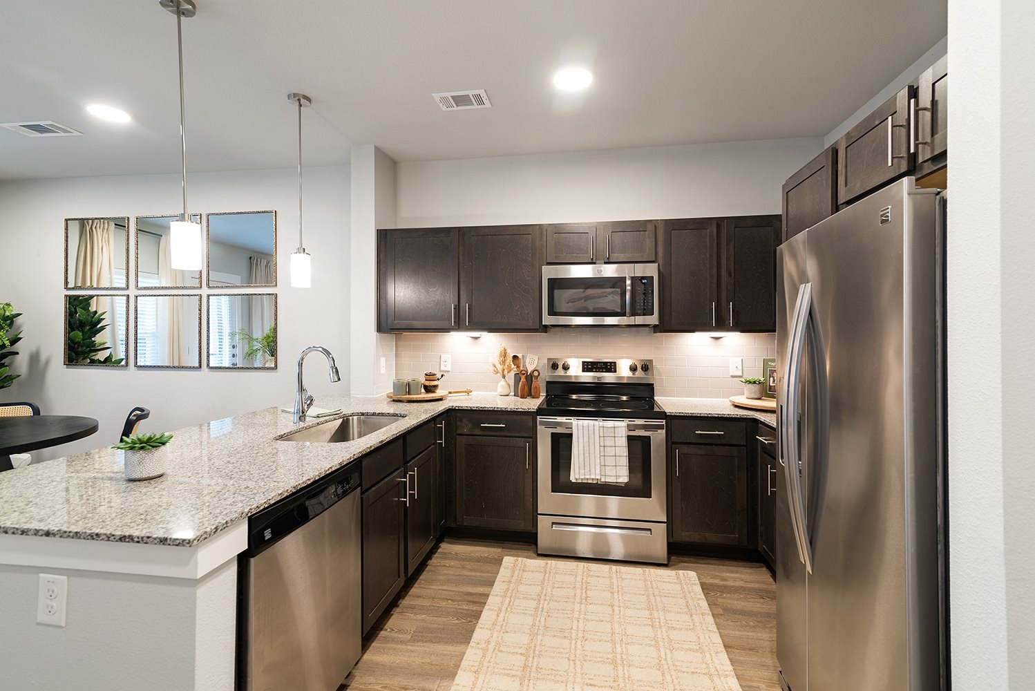 A modern kitchen with dark brown cabinets and stainless steel appliances.