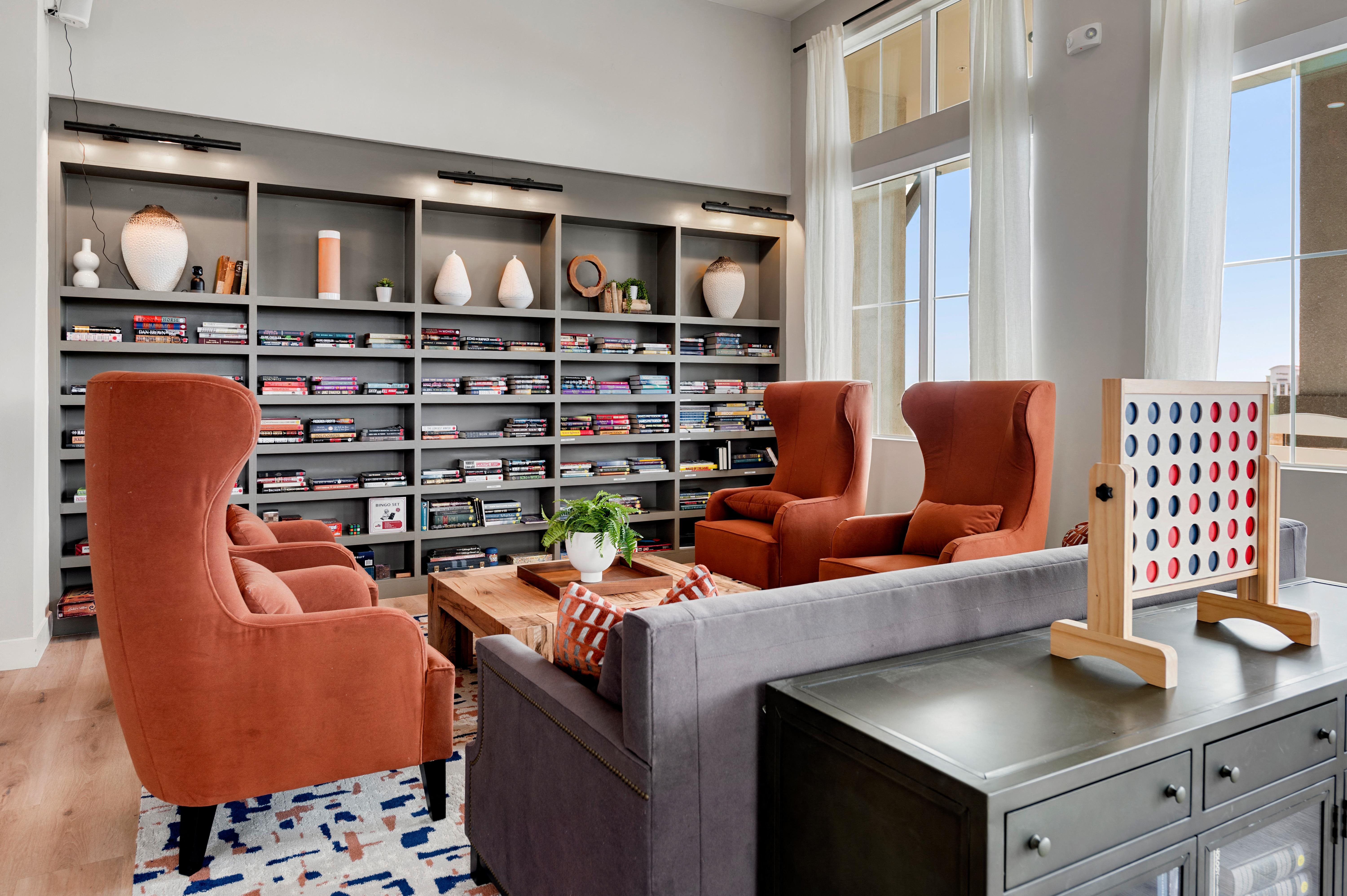 a living room with orange chairs and a bookshelf