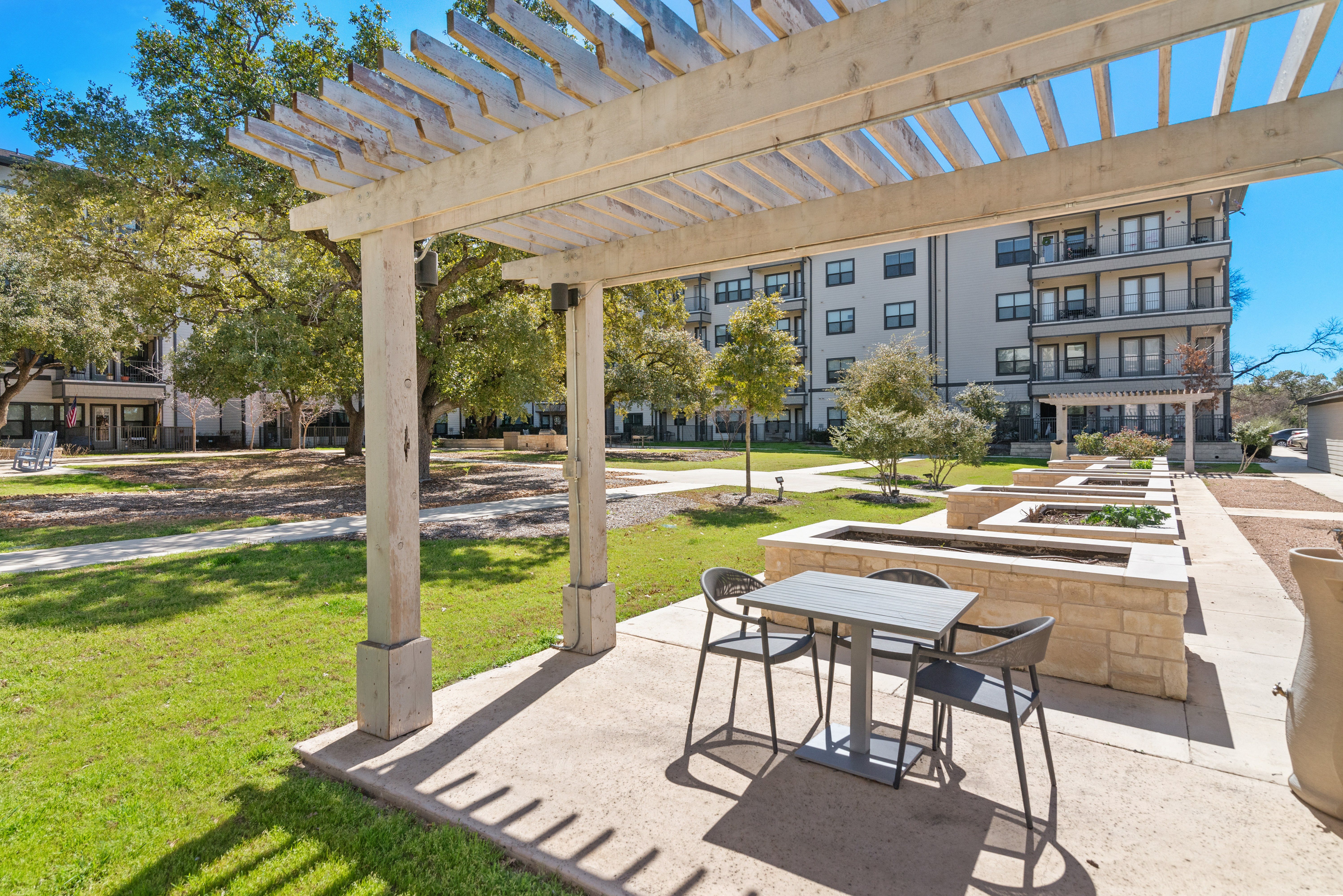 a patio with a table and chairs under a pergola at a senior apartment community