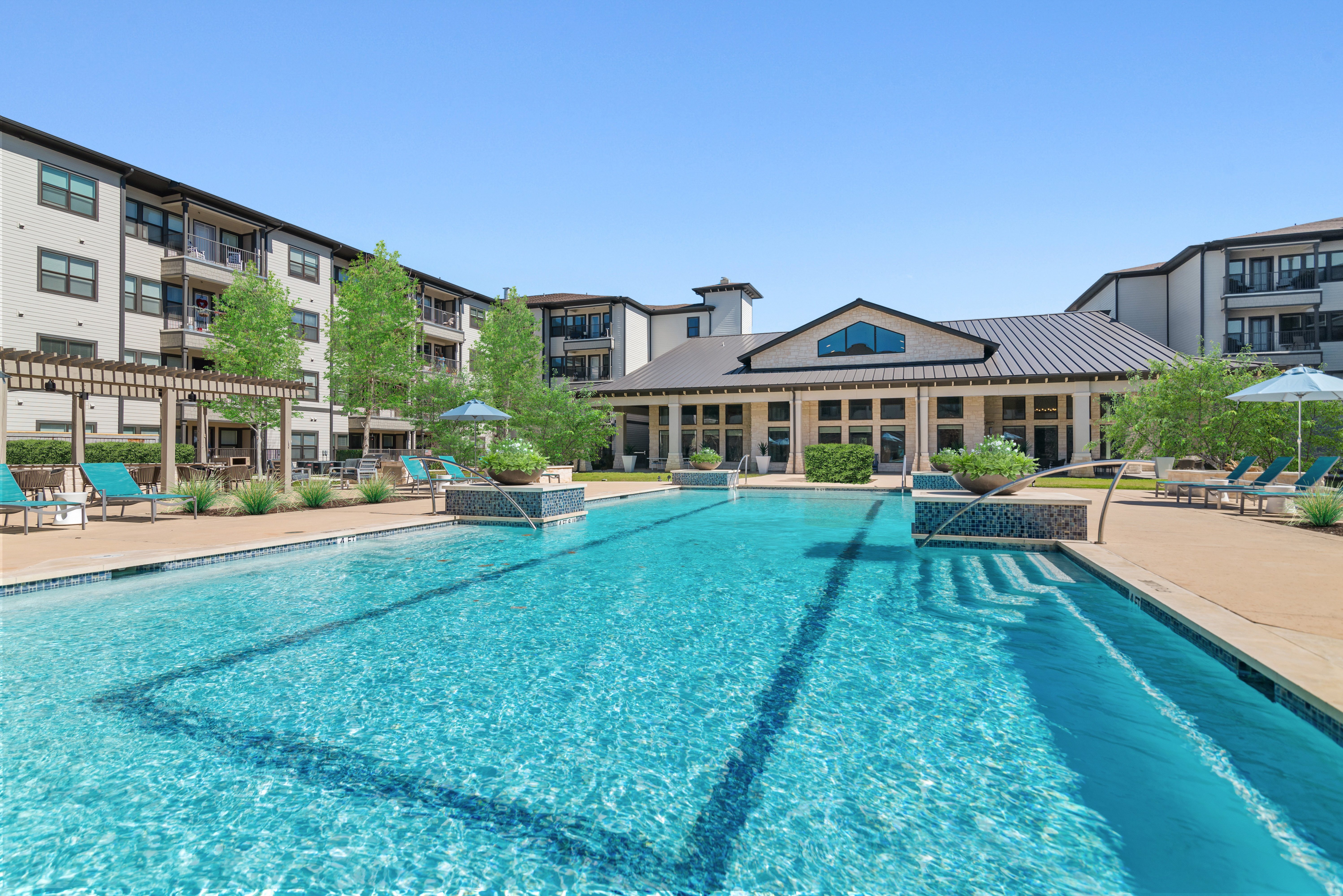A large swimming pool in front of a building with a pool house.